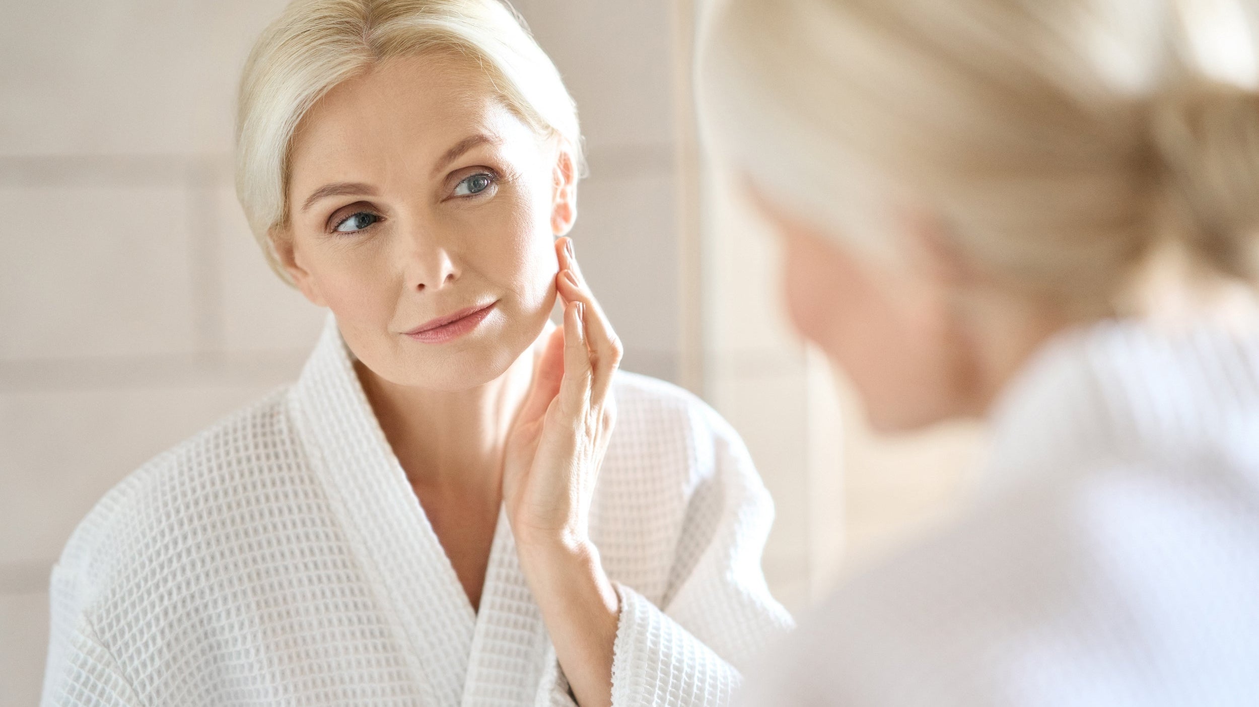 A woman looks in the mirror at her skin. Your skincare routine doesn't have to end when you go to bed. In fact, how you sleep can play a significant role in how your skin ages over time. Read more about how our anti-aging pillow can help.