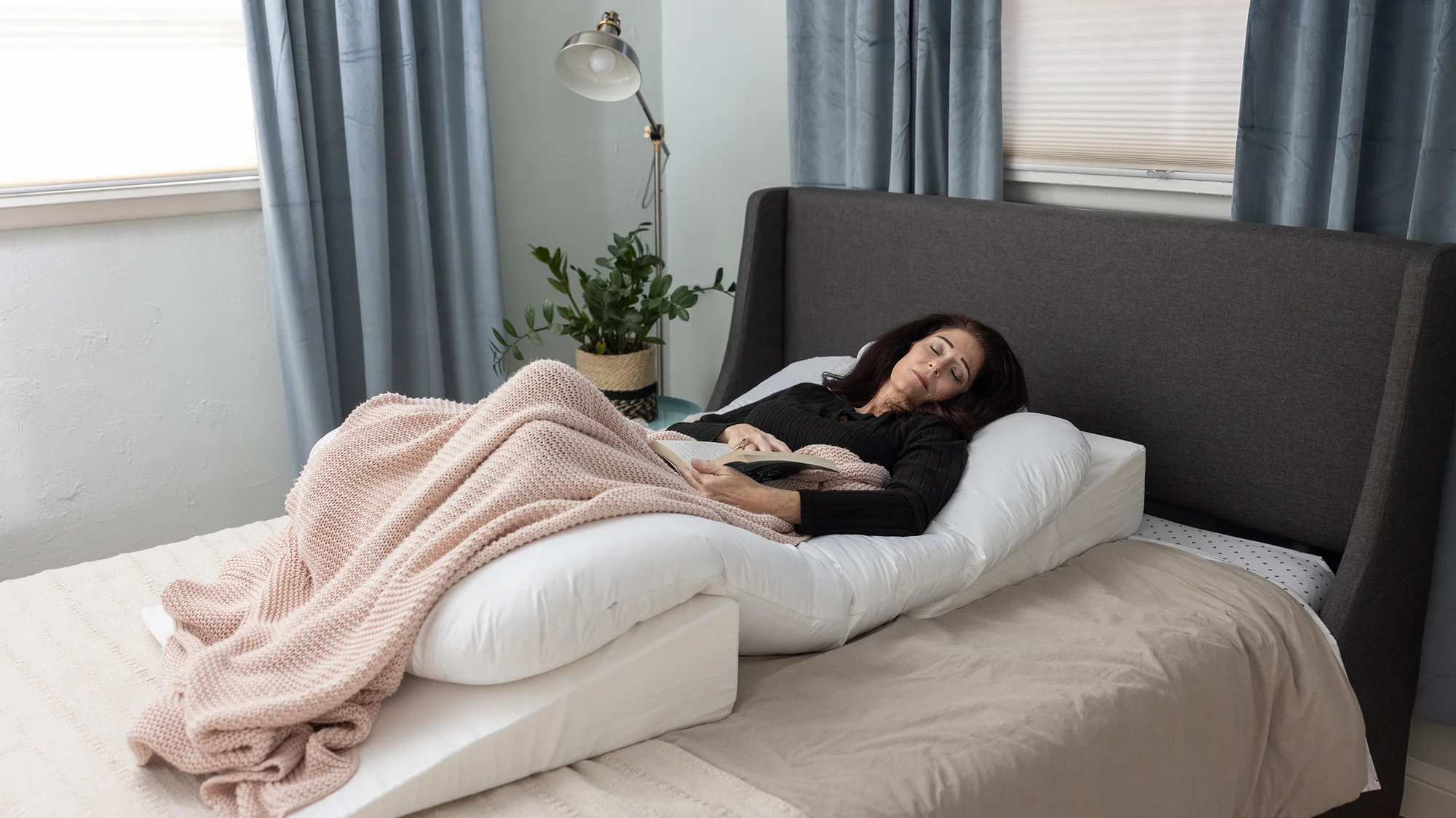 A woman rests in bed using the Sleep Again Pillow System. If you're looking for the best bed rest pillow, we've got your covered.