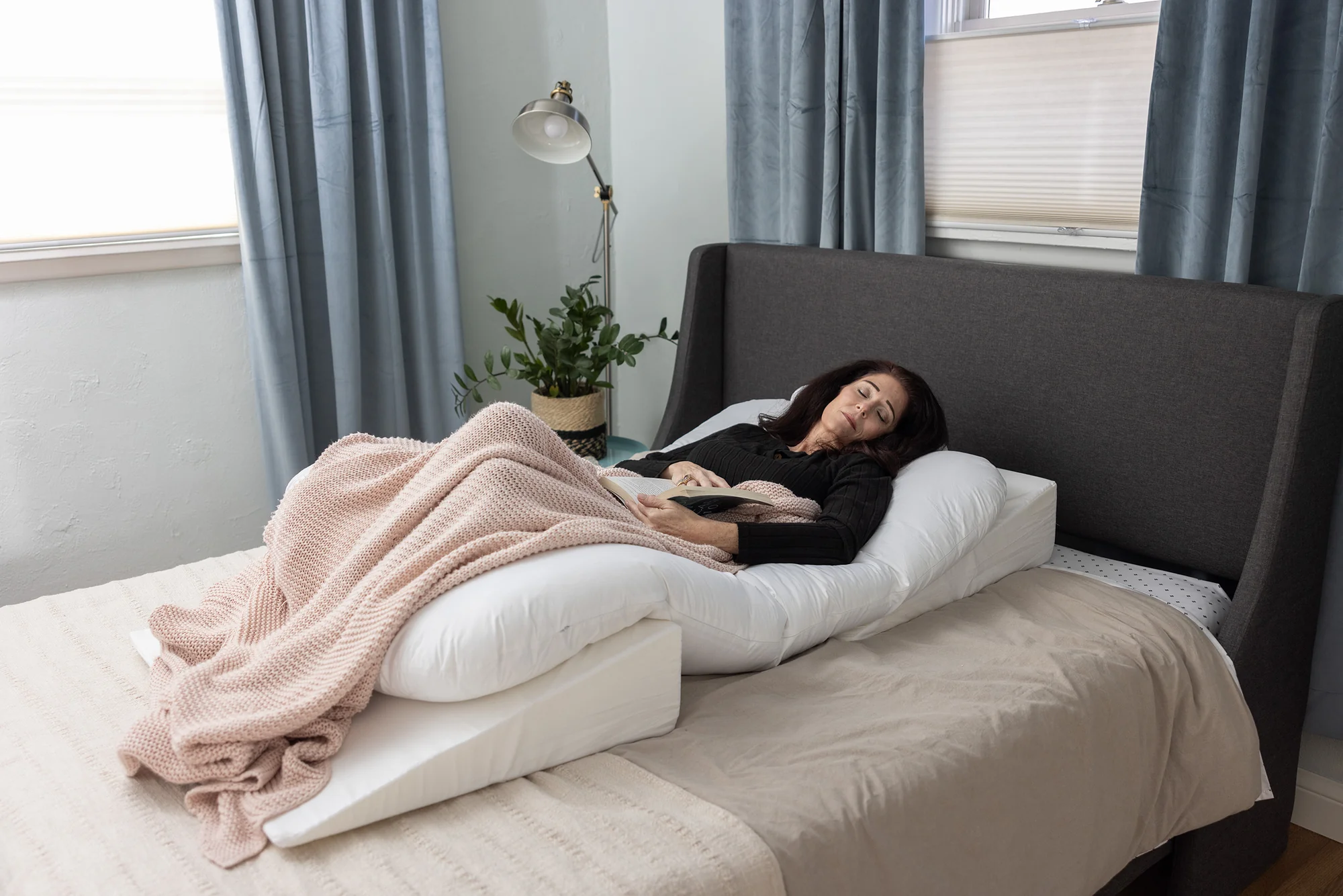 A woman rests in bed using the Sleep Again Pillow System. If you're looking for the best bed rest pillow, we've got your covered.
