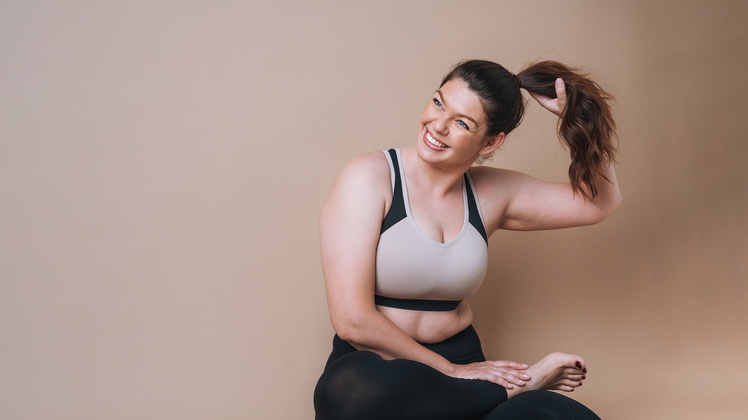 A fit woman sits in a yoga studio. Which sleep position is best for large breasts? Learn more in our complete guide.