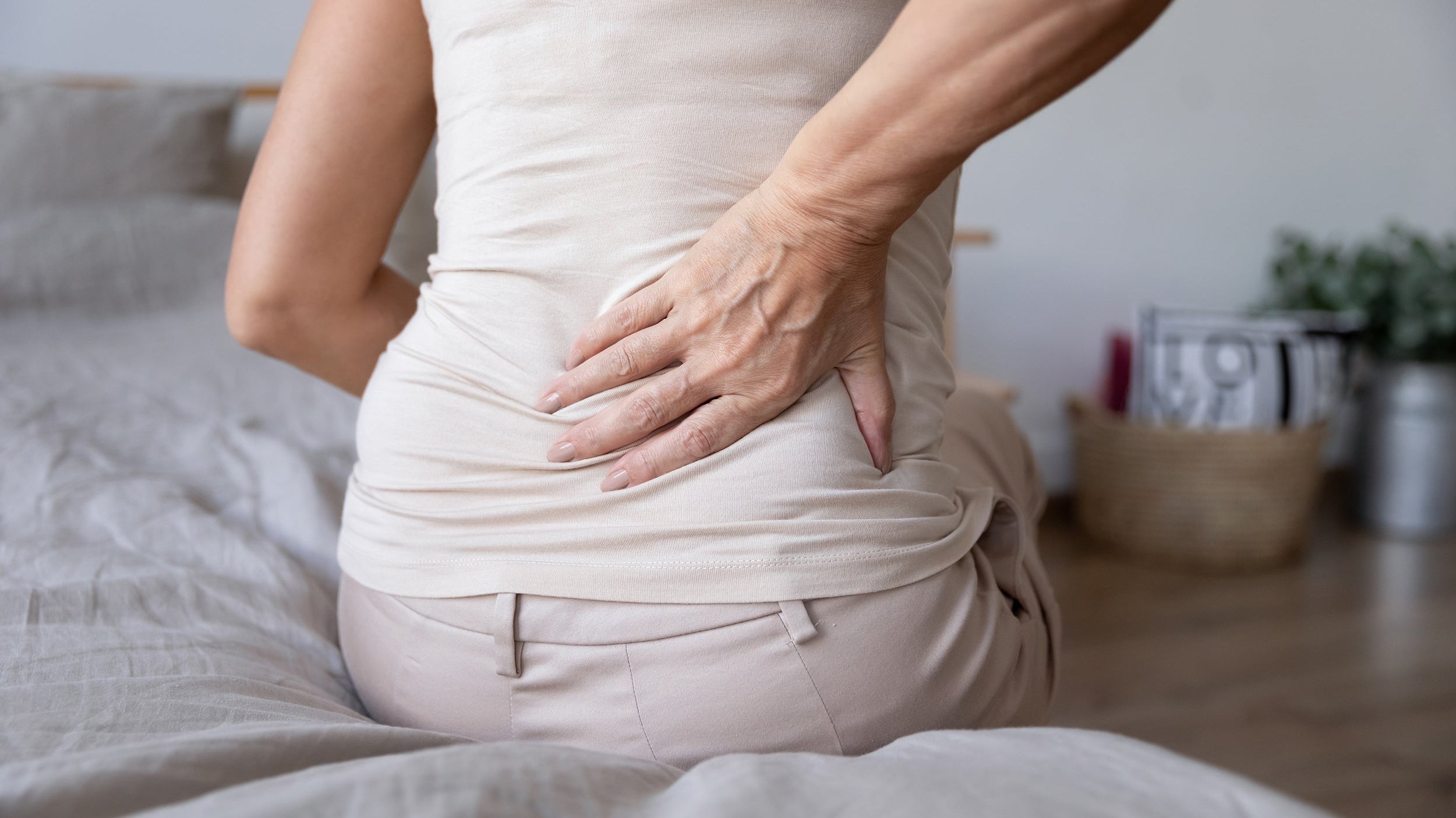 A woman clutches her back in pain. Discover the best sleeping positions for sciatica relief. Learn elevation angles, pillow placement, and positioning strategies that reduce nerve pain tonight.