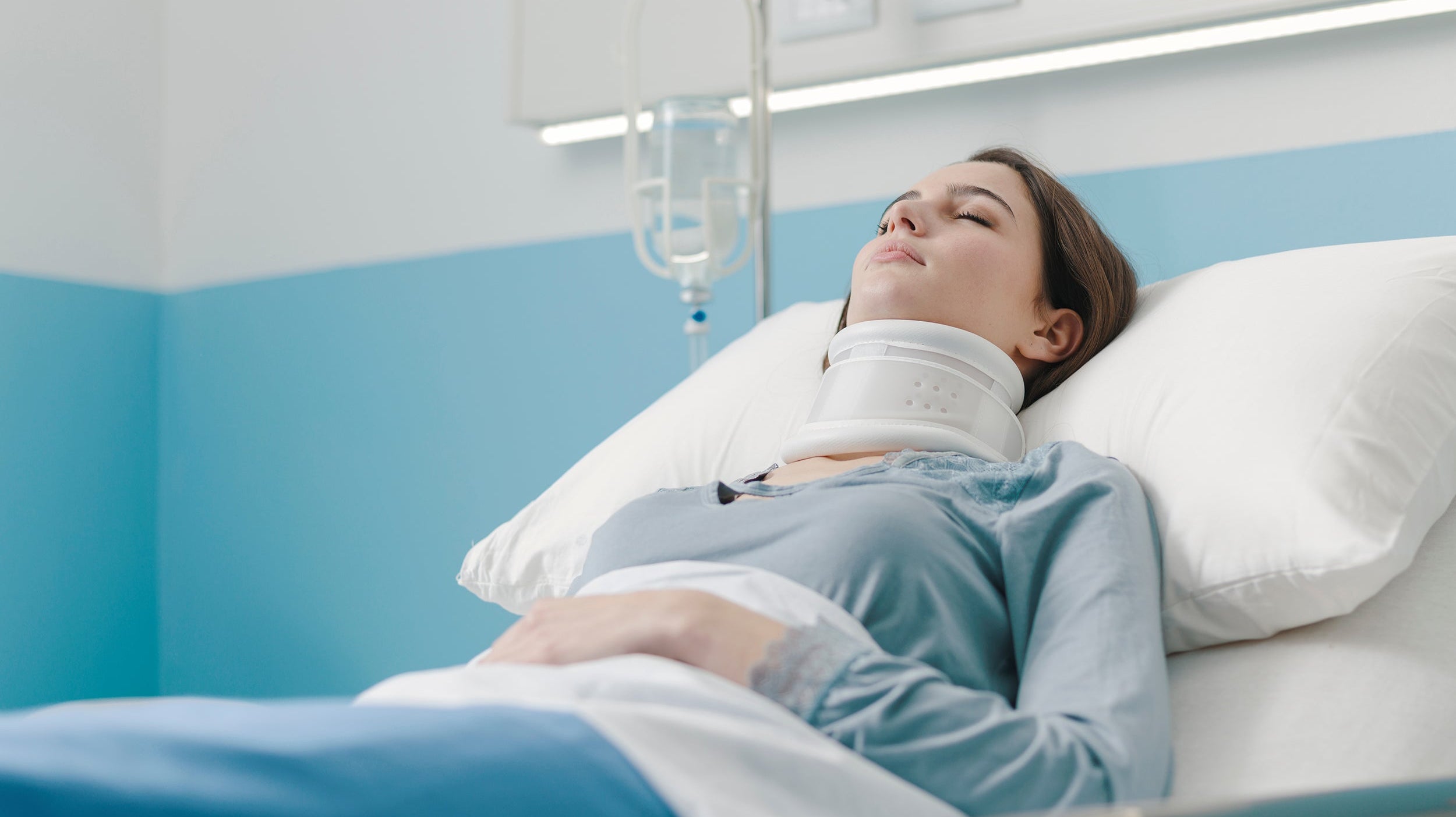 A woman rests in a hospital bed following neck surgery. Learn more about how to get the rest and sleep you need after cervical neck surgery in our comprehensive guide.