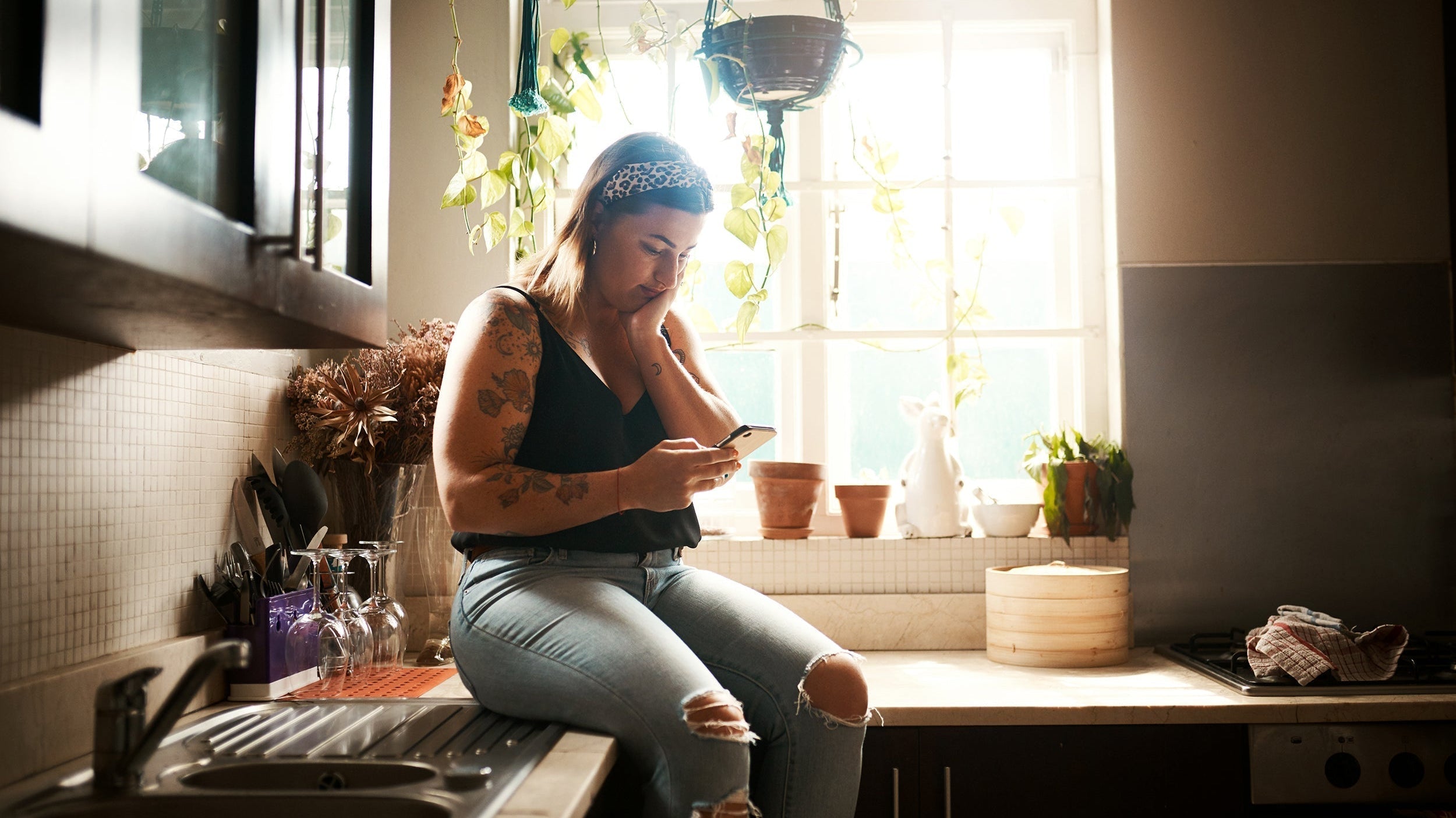 A woman looks at her phone. Sleep after Lipo 360 is tough. This guide covers what to do and what to avoid.