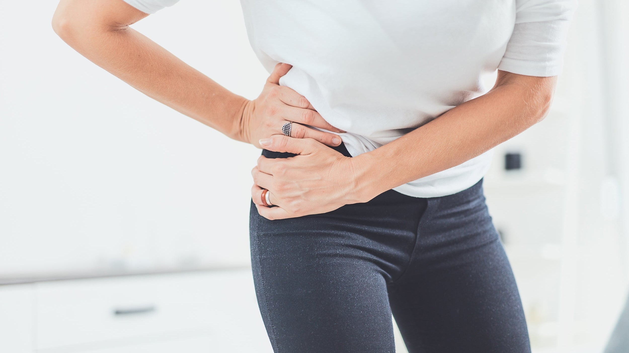 A woman clutches her hip in pain. Hip pain affects millions worldwide and its impact on sleep can be devastating. Learn how to sleep with hip pain in our complete guide.