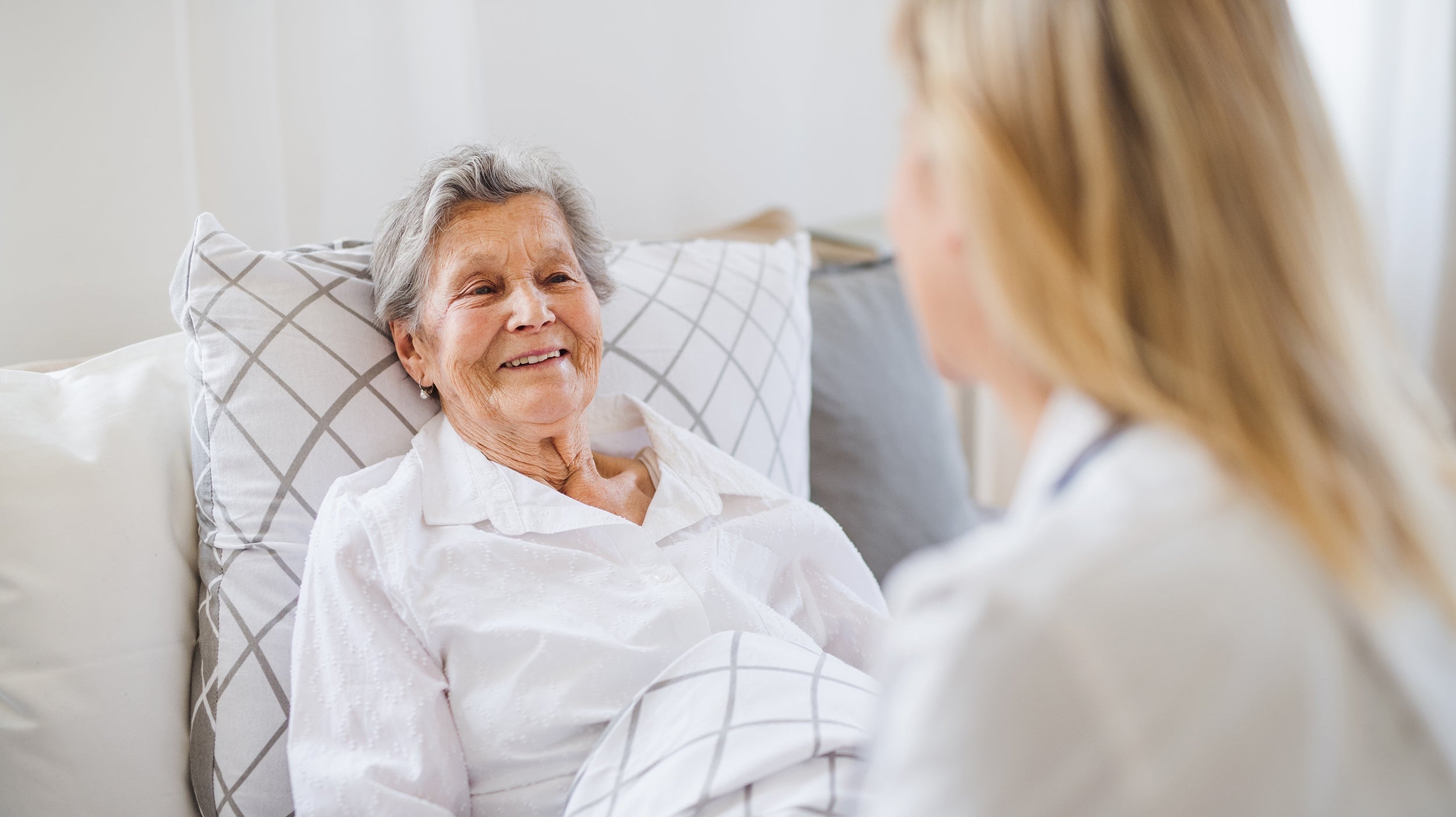An elderly woman rests in bed. If you're caring for an elderly or disabled loved one, explore our article on positioning pillows for the elderly and help them get better sleep today.
