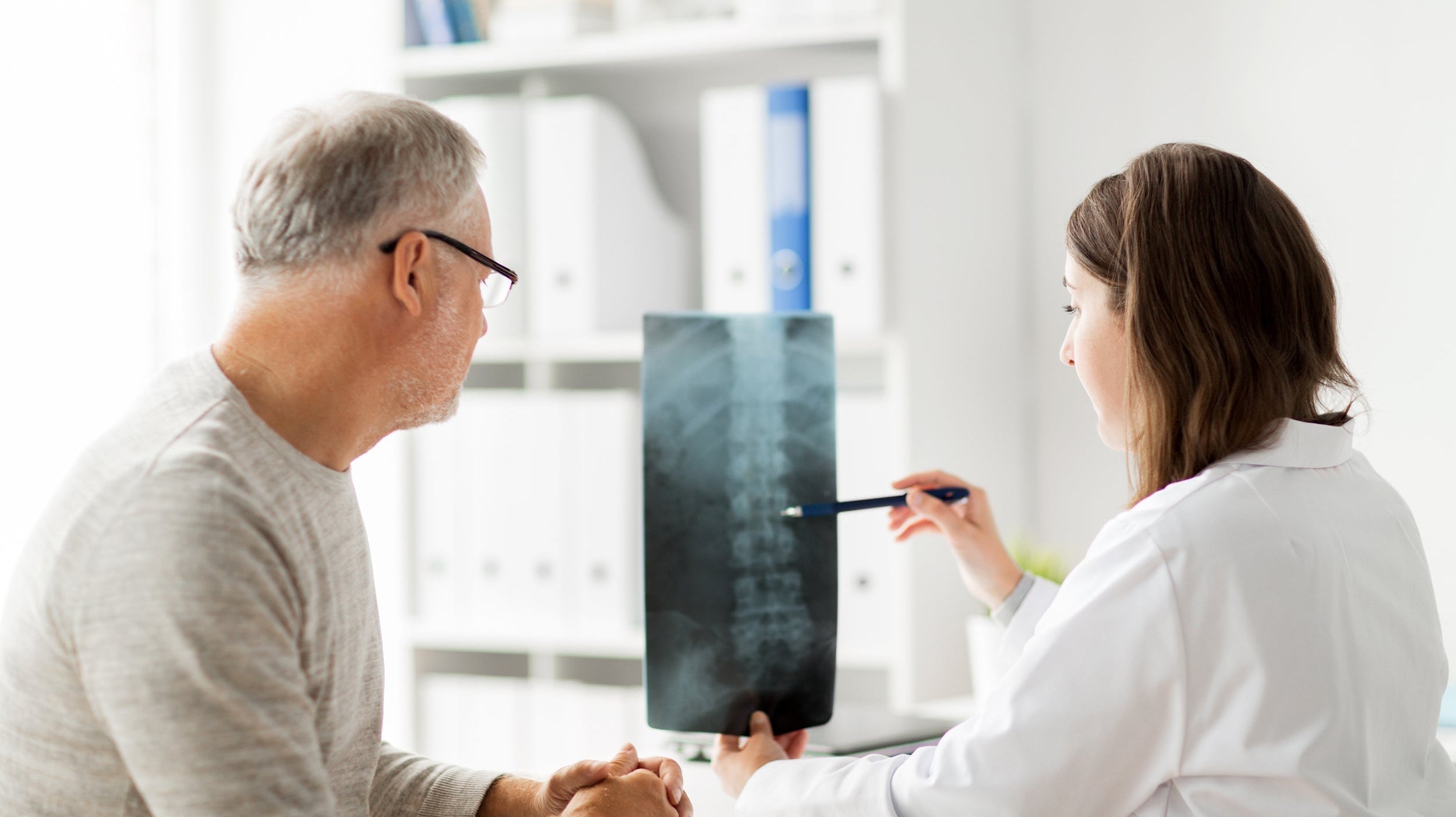 A doctor reviews an X-ray of a patient's spine. In preparing for epidural steroid injection, how you sleep can have a big impact on healing and the overall results. Read more in our complete guide.