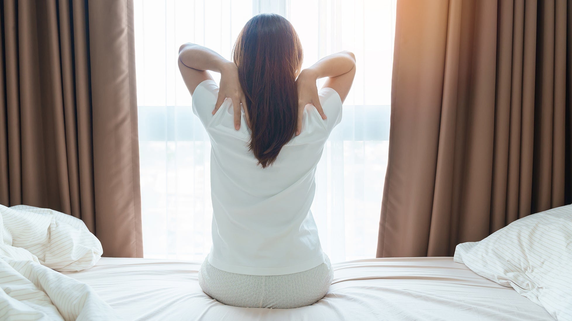 A woman clutches her upper back. End morning upper back pain with proper sleep positioning. Learn why elevated back sleeping supports your thoracic spine and prevents shoulder blade strain all night.