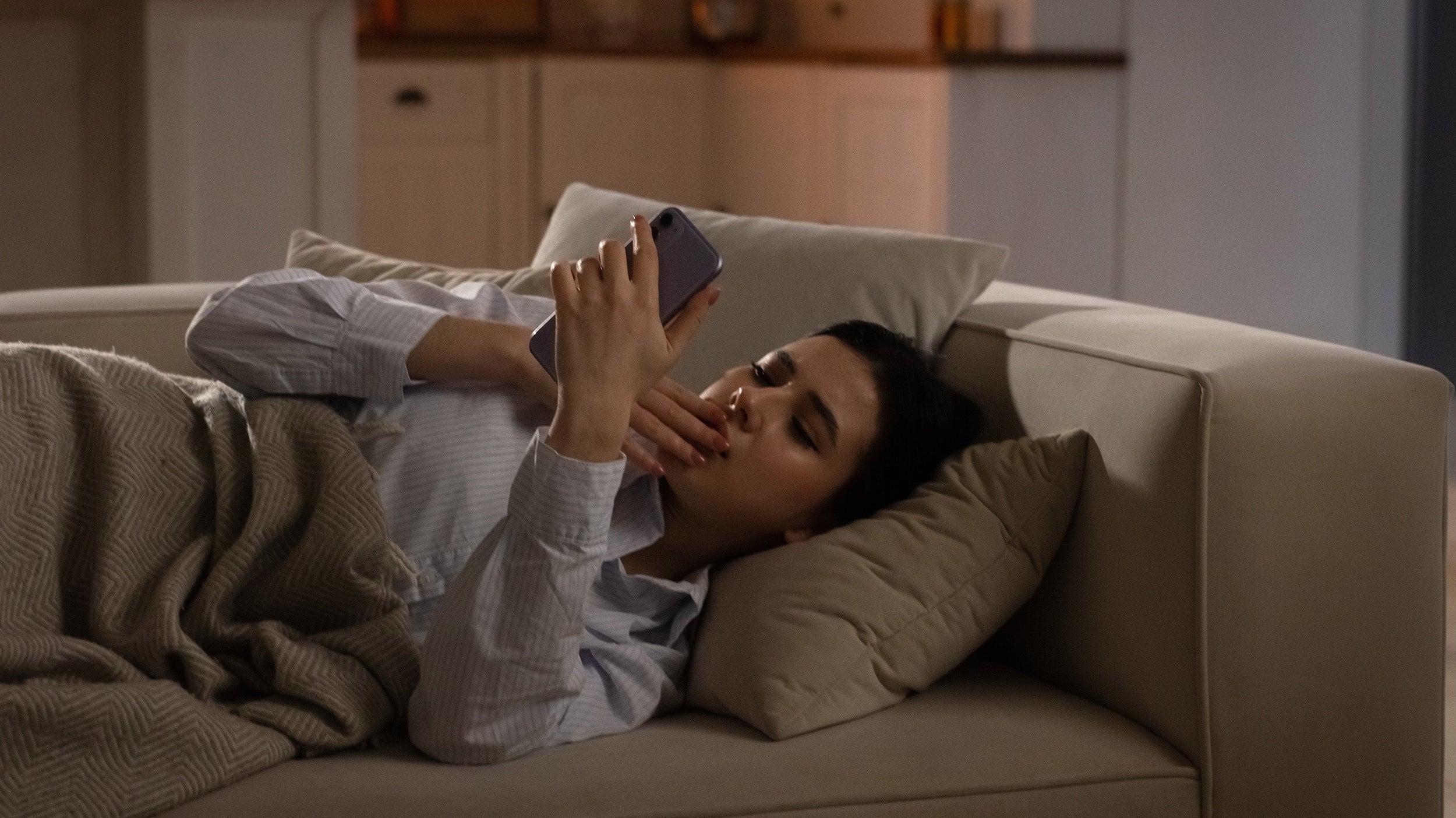 A woman rests on the couch. Wondering when you can finally side sleep after breast augmentation? Get the week-by-week timeline, what affects your clearance, and how to make the transition comfortable.