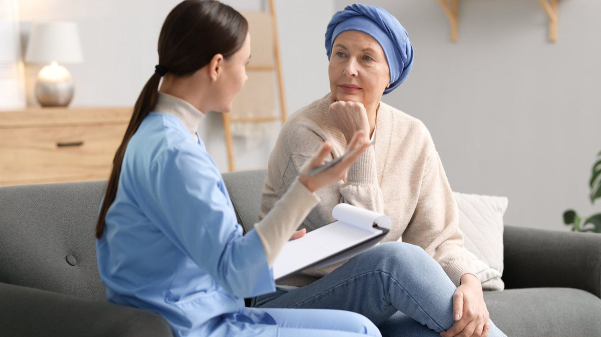 Woman with bonnet siting with woman with scrubs and a clipboard.