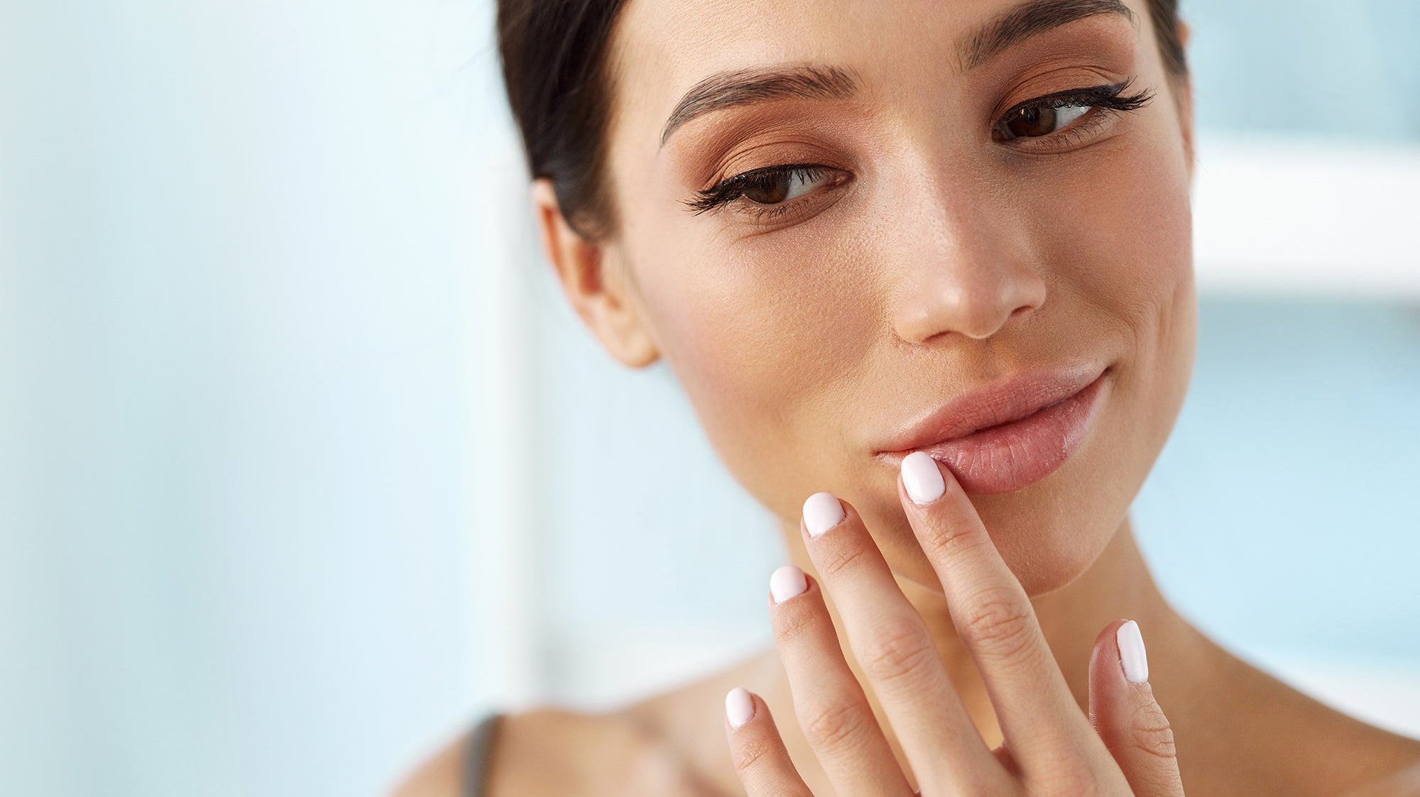 A woman looking at her lips. Planning a lip lift? Learn why elevated back sleeping controls swelling, how long you'll need it, and how to set up your recovery before surgery day arrives
