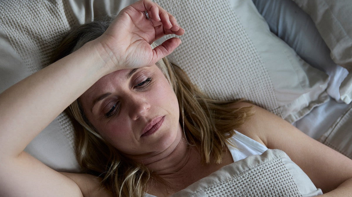 Woman lying awake in bed, struggling to get comfortable during post-surgical recovery