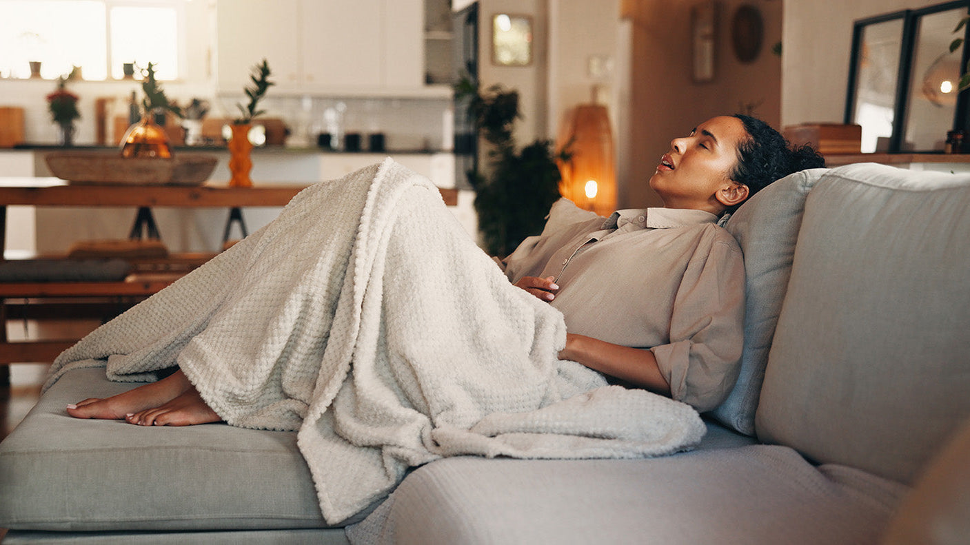 A woman in discomfort. How to sleep with acid reflux on GLP-1 medications: the causes, the ideal 30-45 degree sleep angle, and the positioning system that holds that angle all night.