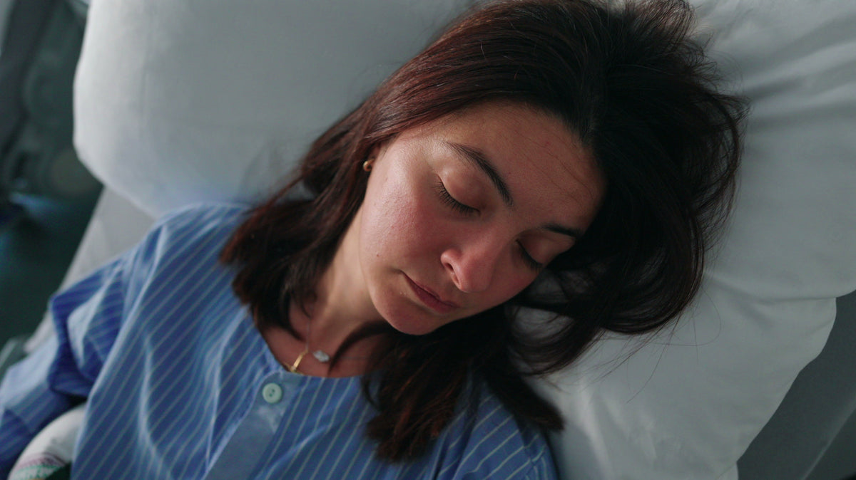 Woman sleeping in hospital bed.