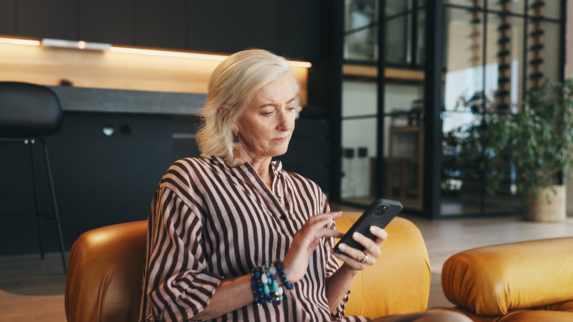 A woman looks at her phone. Explore our complete guide on mastectomy recovery must-haves, created by a breast cancer survivor, and be prepared before surgery.