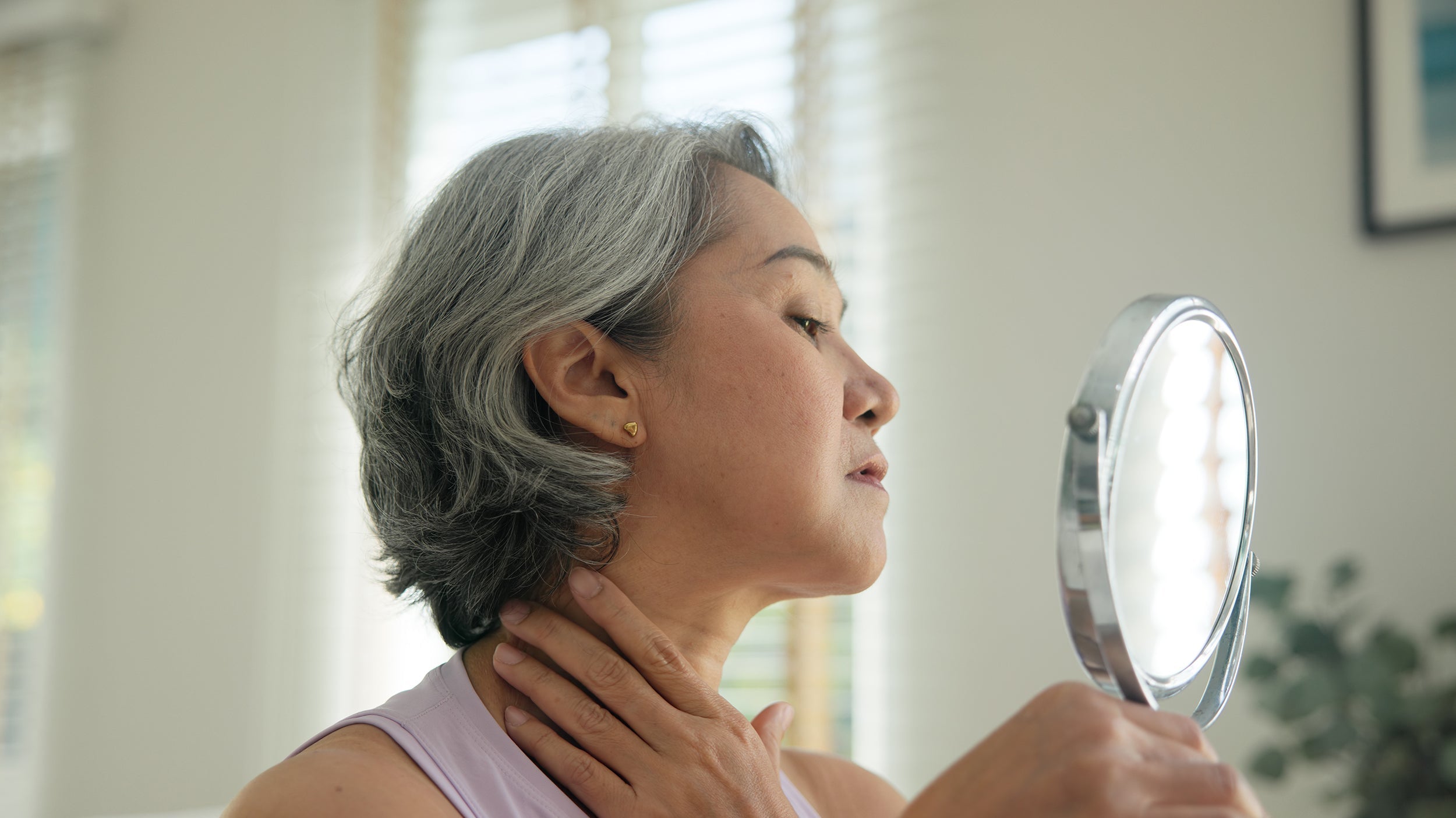 A woman looking in the mirror. Surgeons require elevated sleep for weeks after cosmetic surgery. See the 14 recovery must-haves that proactive patients should prepare before their procedure date, not after.
