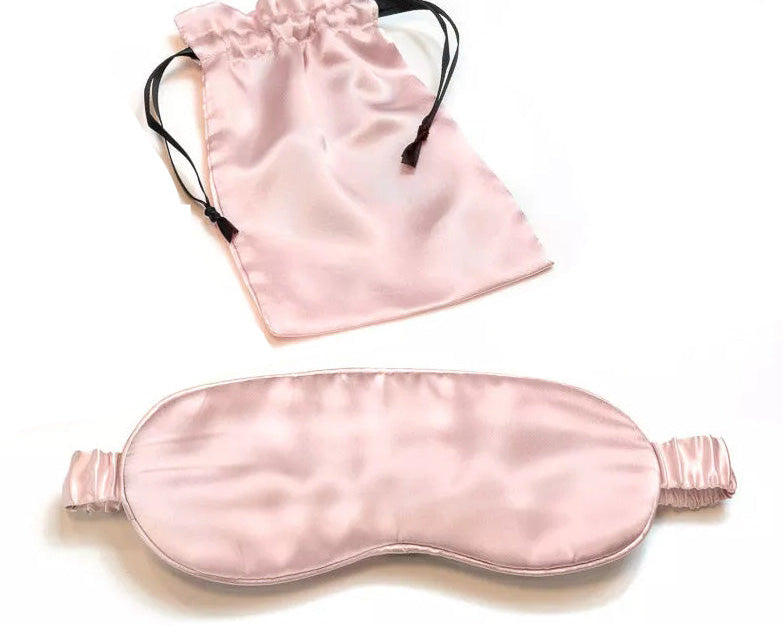 A light pink Mulberry Silk Sleep Eye Mask with silk covered elastic strap is shown below a matching satin drawstring pouch on a white background.