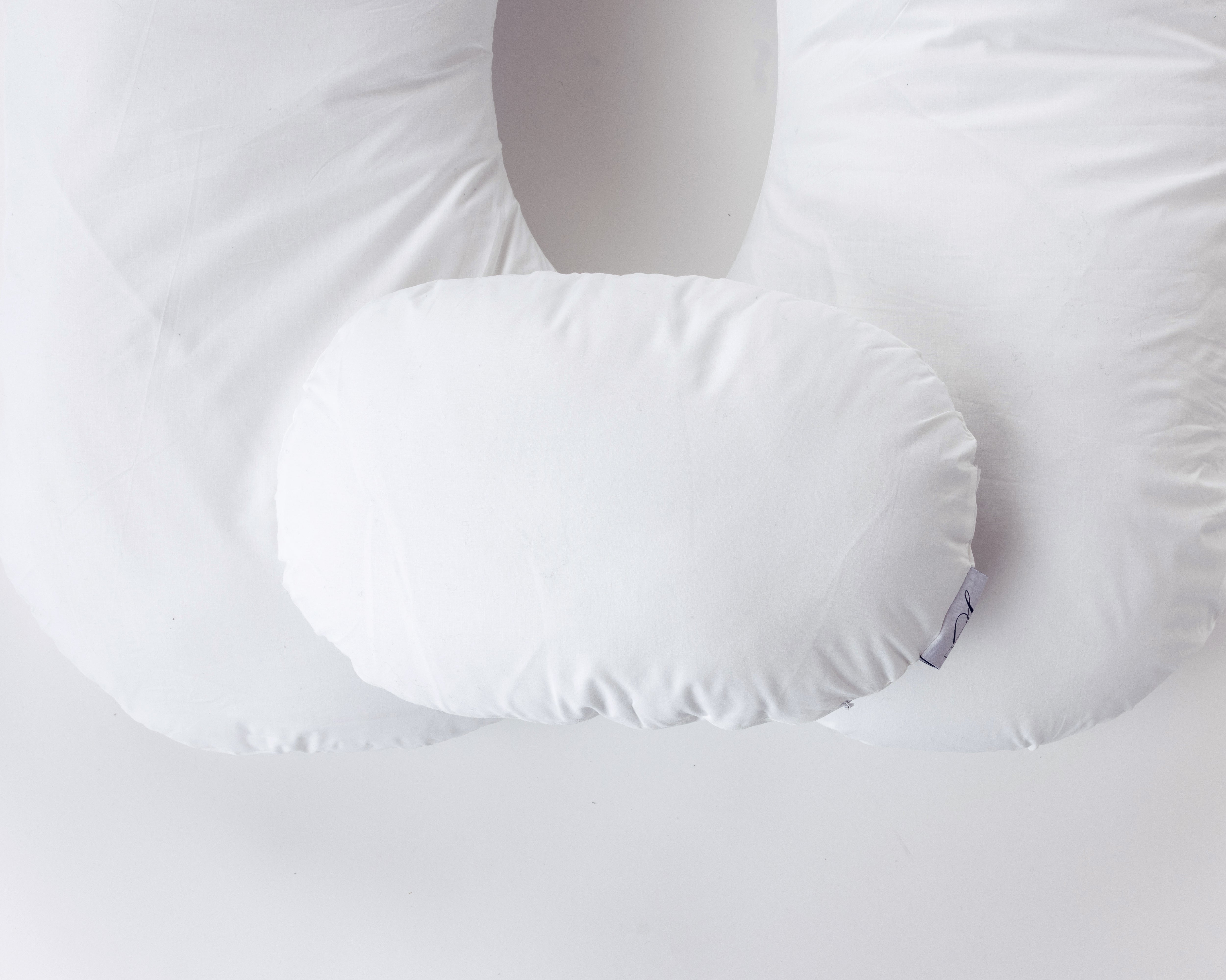 Two white, oval-shaped side pillows from "Two Side Pillows Sold Separately" are displayed atop a contoured body pillow with a washable slipcover, all arranged against a plain white background.