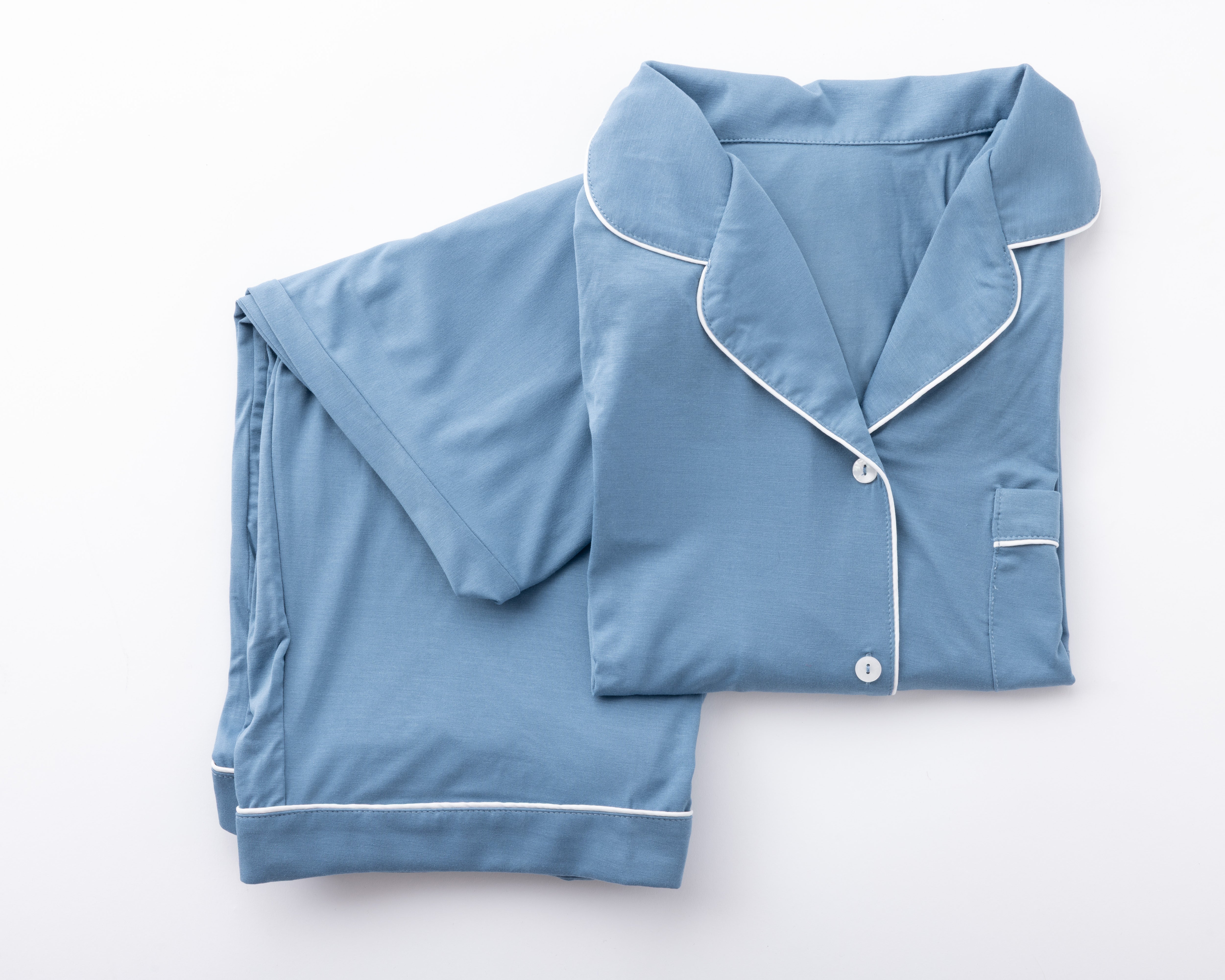 Product image of a blue pajama set with white piping folded neatly on a white background