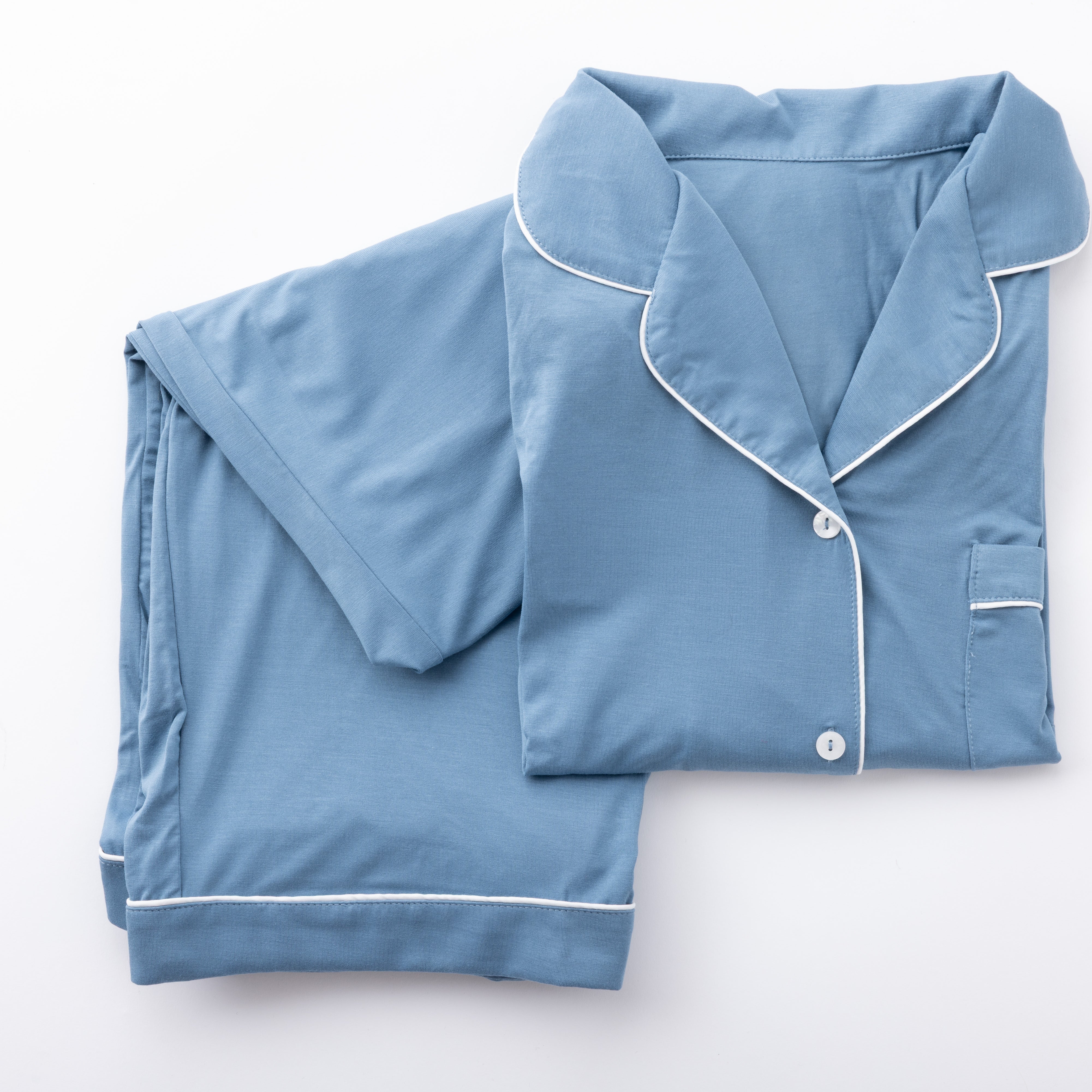 Product image of a blue pajama set with white piping folded neatly on a white background
