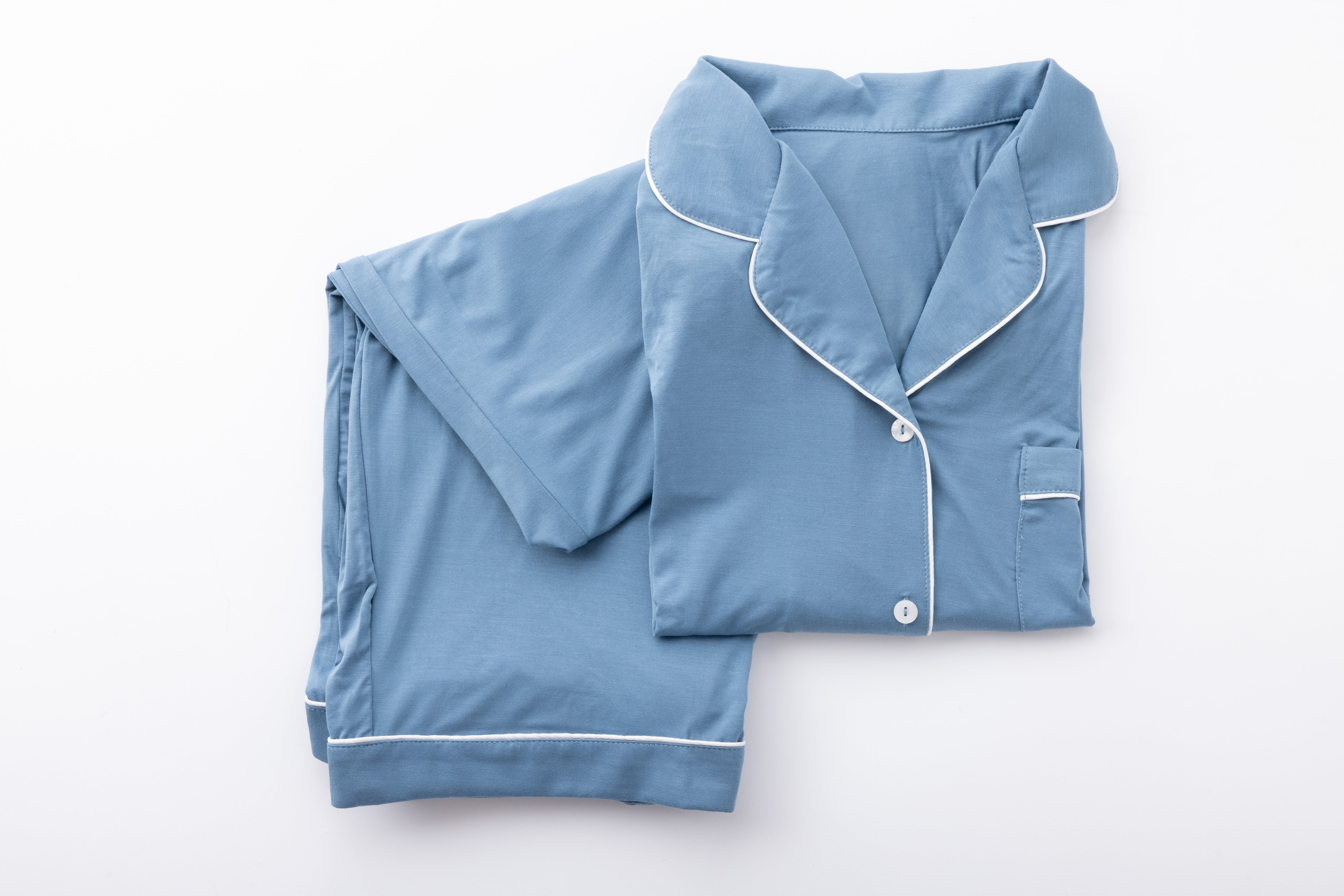 Product image of a blue pajama set with white piping folded neatly on a white background