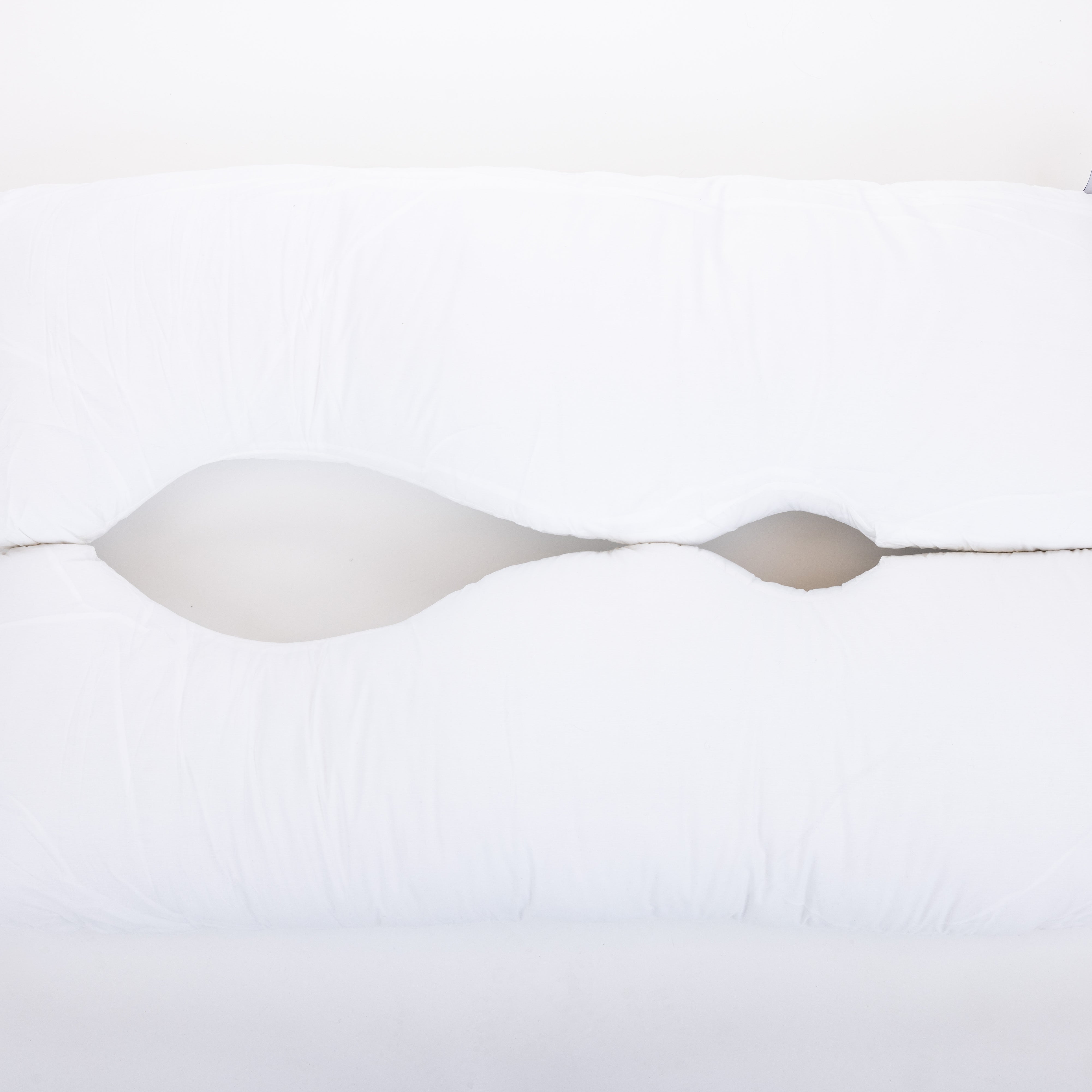 The "Two Side Pillows Sold Separately" is a white, uniquely contoured bedding pillow with a wave-like center cutout, shown on a plain white background.