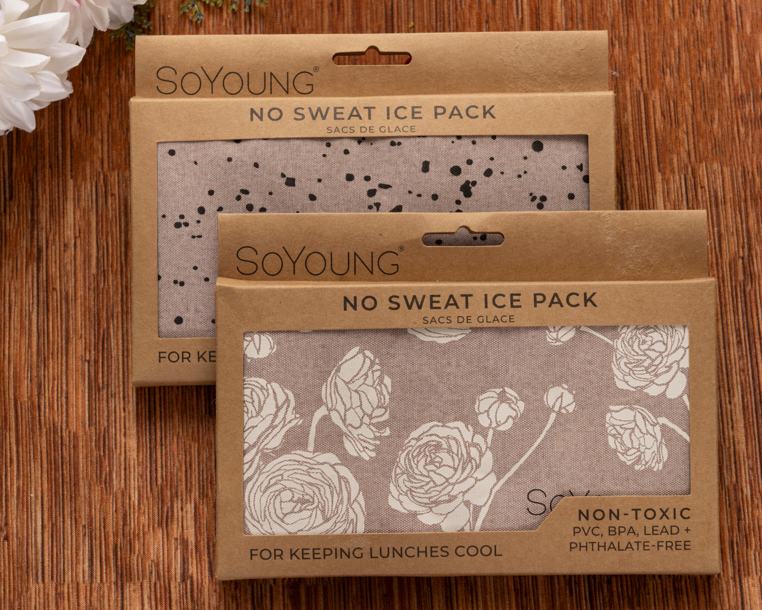 Two SoYoung “No Sweat Ice Pack” products—one with a black splatter design, one with a white floral pattern—are displayed on wood, ideal for including in The Best Mastectomy Care Package.
