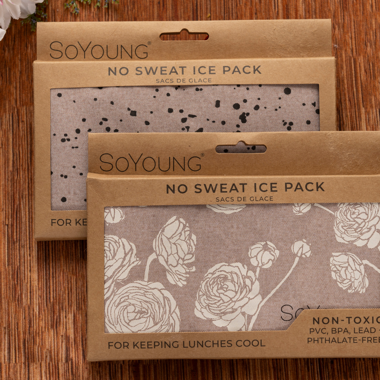 Two SoYoung “No Sweat Ice Pack” products—one with a black splatter design, one with a white floral pattern—are displayed on wood, ideal for including in The Best Mastectomy Care Package.