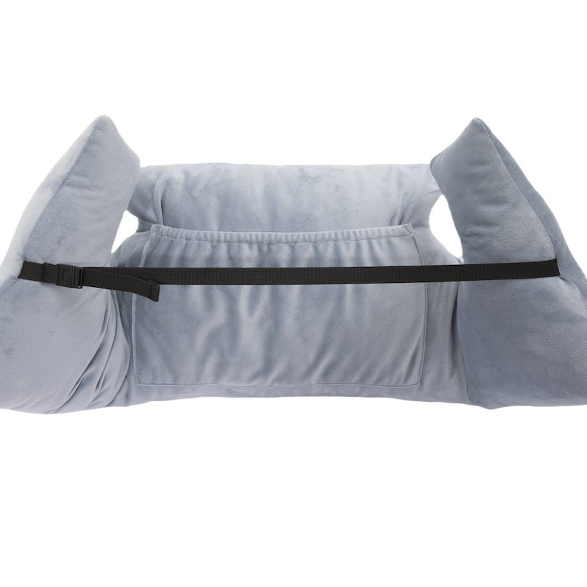 The Chest Pillow is light gray, plush, and features two large side supports, a black adjustable front strap, and a central pocket for positioning and stability after breast surgery. Shown on a white background.