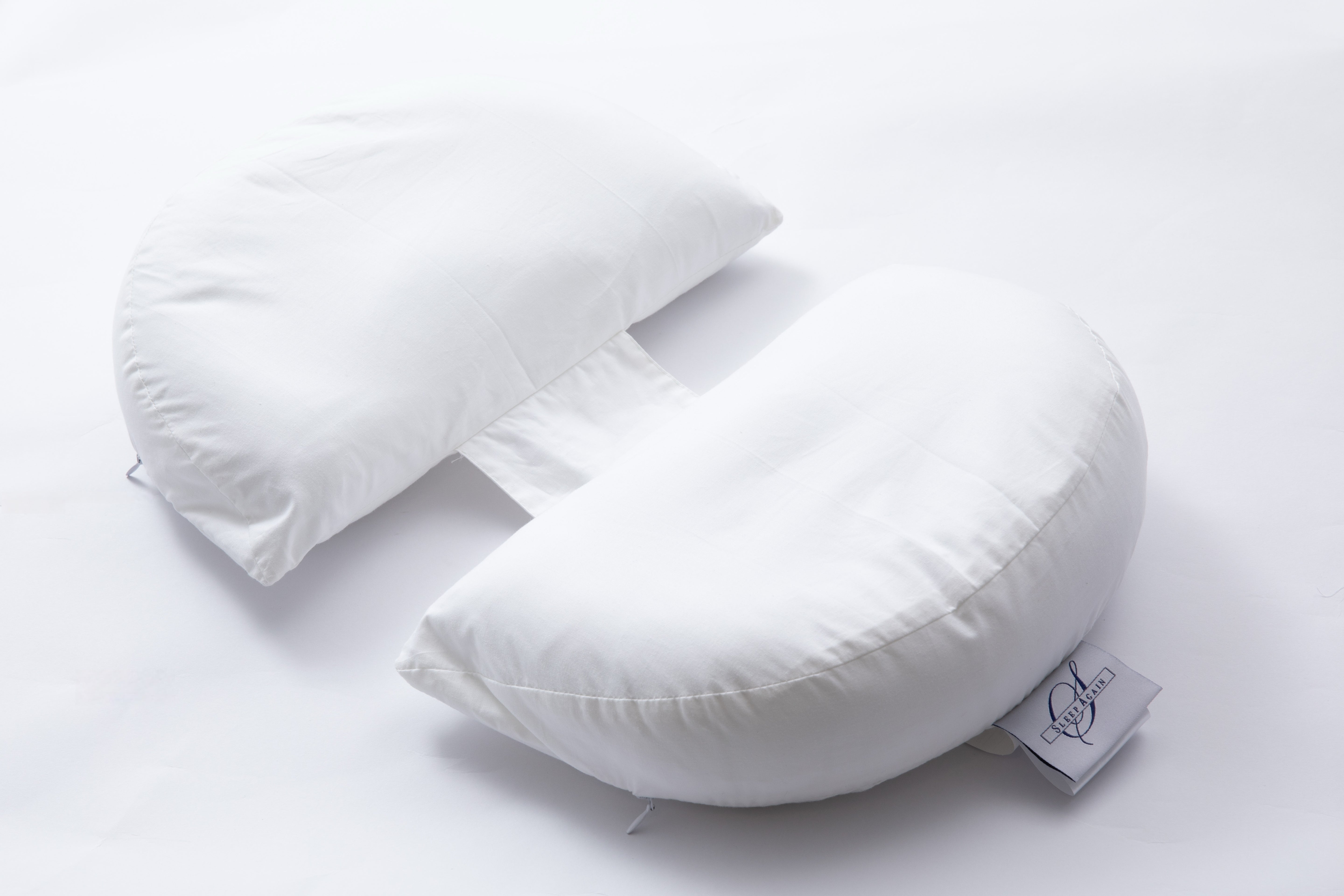 The Side Sleeping Chest Pillow, a butterfly-shaped white pillow with a curved center gap and fabric strip, is shown on a white background. A logo tag accents one side, making it ideal for post-surgery breast support.