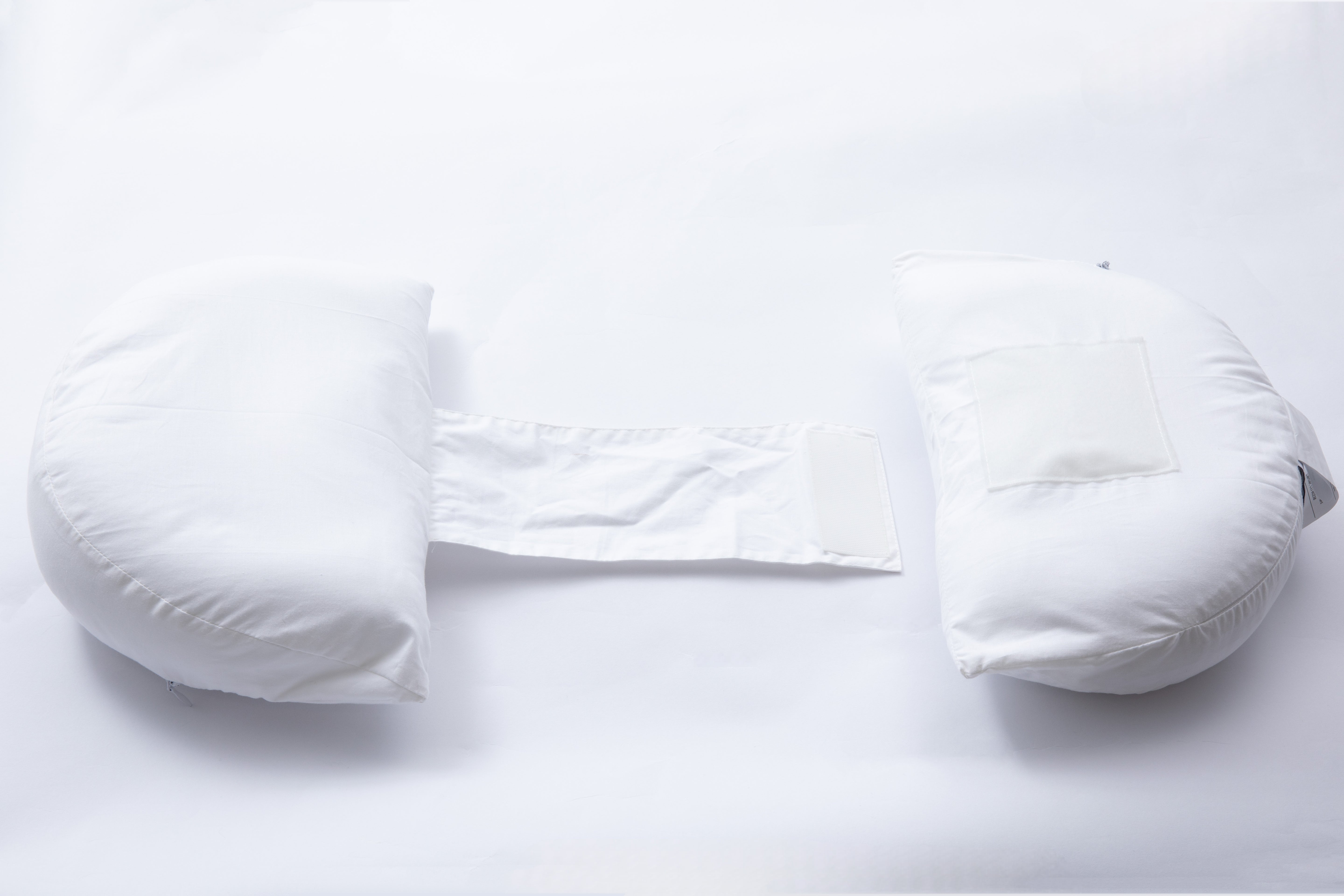 The Side Sleeping Chest Pillow is a white breast surgery pillow with two half-moon cushions joined by a central fabric strap, designed for post-surgery support and comfort while side sleeping, shown against a white background.