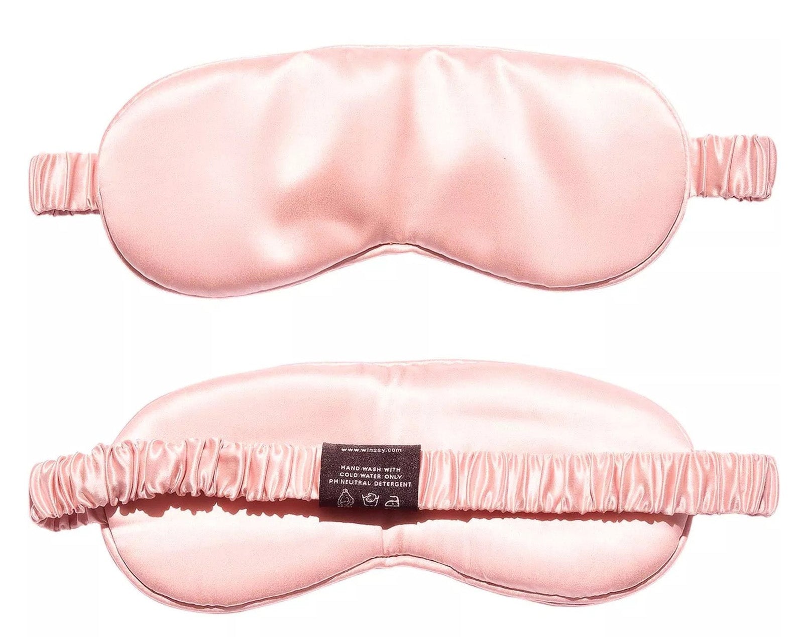 Two light pink Mulberry Silk Sleep Eye Masks are displayed—one shows the smooth front, the other highlights the silk-covered elastic strap and care label, emphasizing the mask’s elegant design and luxurious material.