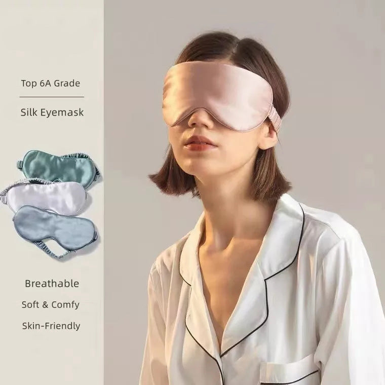 A woman in white pajamas wears a pale pink Mulberry Silk Sleep Eye Mask with Silk Covered Elastic Strap, standing against a neutral background. Eye masks in various colors are displayed nearby, with text noting their soft, breathable qualities.