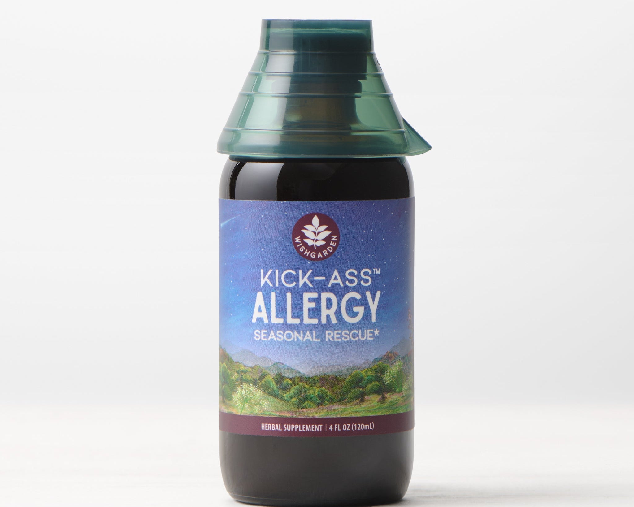 A bottle of Kick-Ass Allergy, Seasonal Rescue tincture featuring a blue and purple label with a mountain design and green cap, displayed on a light surface against a plain background.