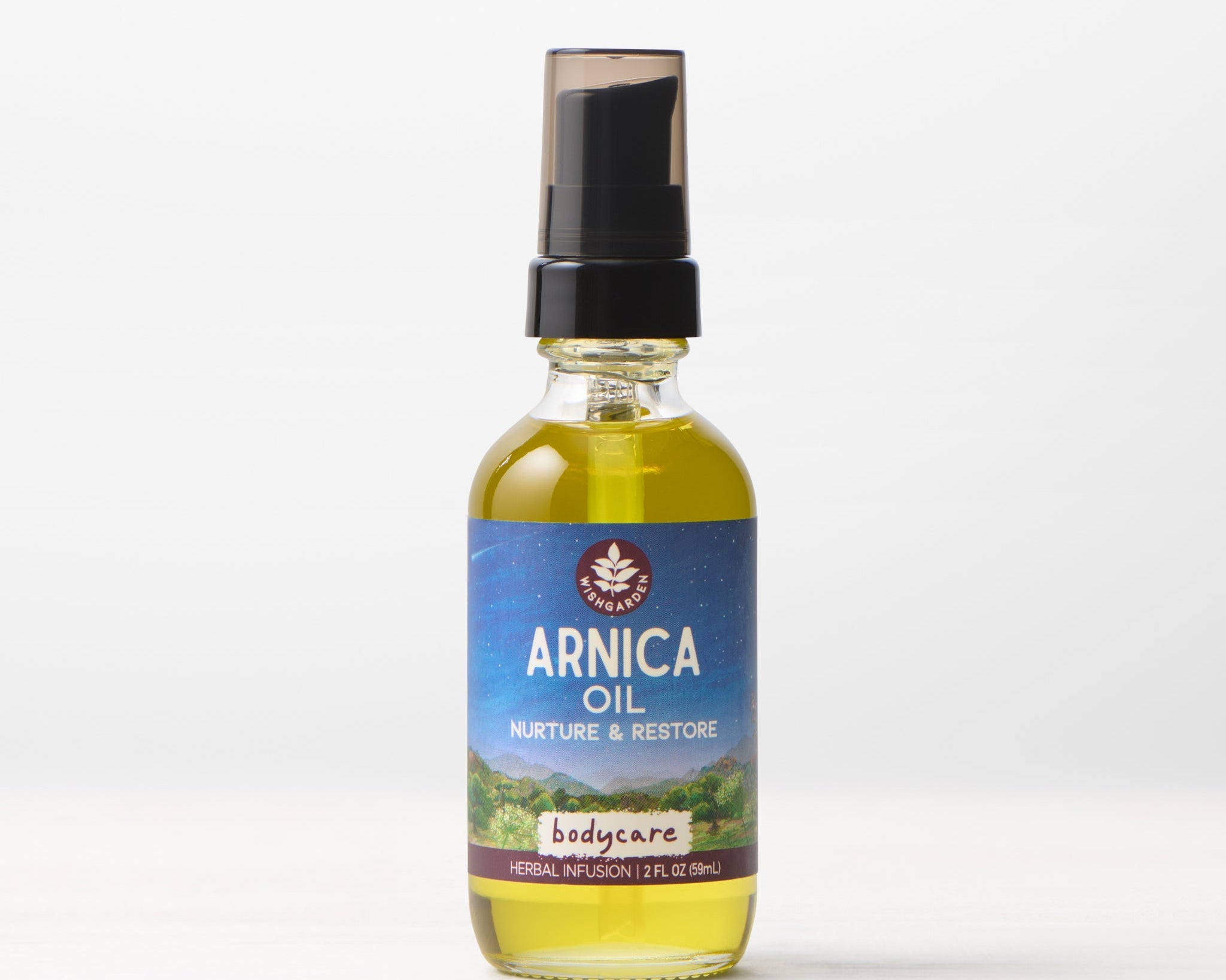 A clear glass bottle of Arnica Oil Nurture & Restore muscle massage oil with a black pump and a blue-purple label, 2 fl oz (60mL), is shown against a light background.