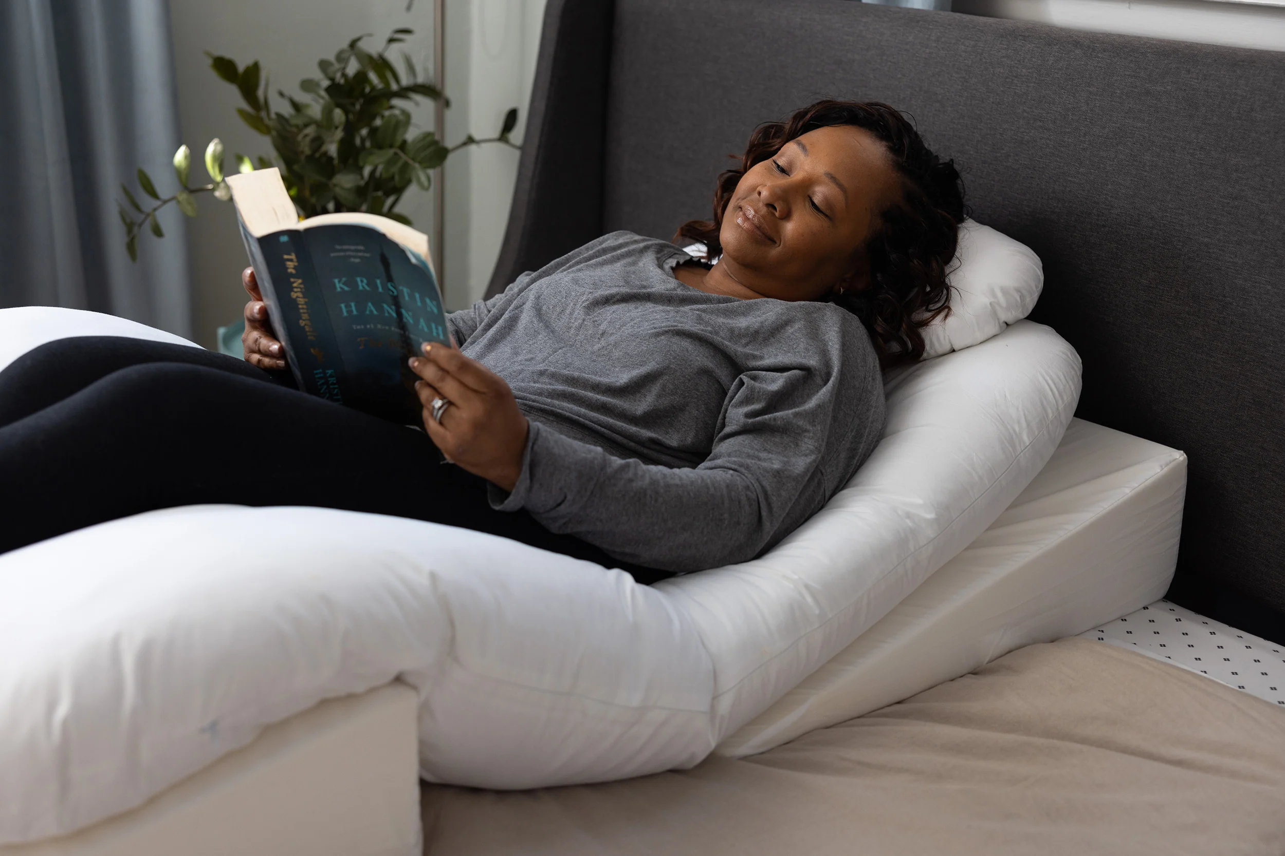 A woman rests on her back using the Sleep Again Pillow System, a BBL pillow designed for back sleeping following a Brazilian butt lift.