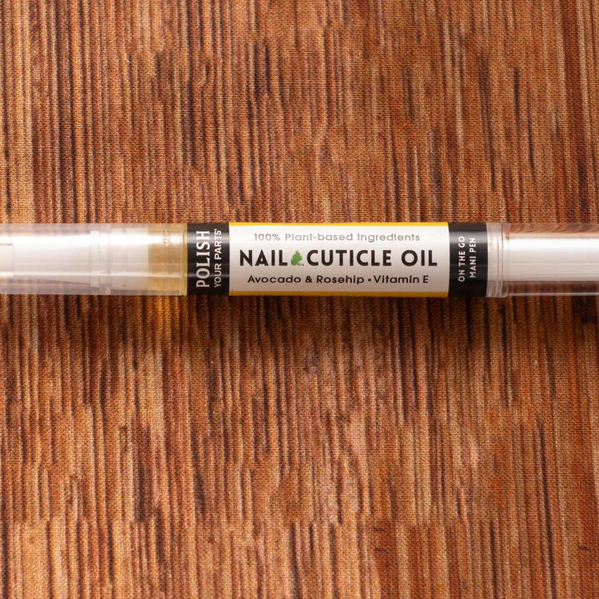 A clear pen-style tube labeled "Premium Soothing Skin & Lips" with a white cap and brush applicator rests on a brown wooden surface—ideal for soothing skin and lips in any cancer care gift box.