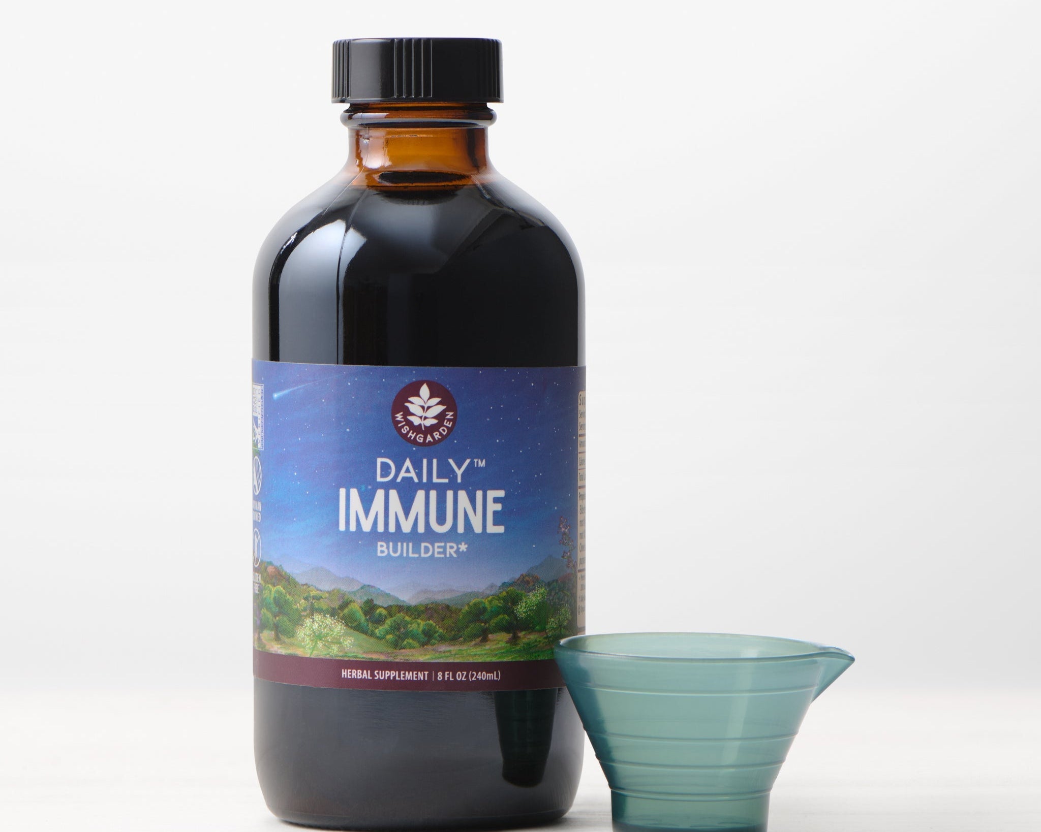 A bottle of Daily Immune Builder with a blue measuring cup sits on a white surface against a plain light background, highlighting this herbal supplement for daily immune support.