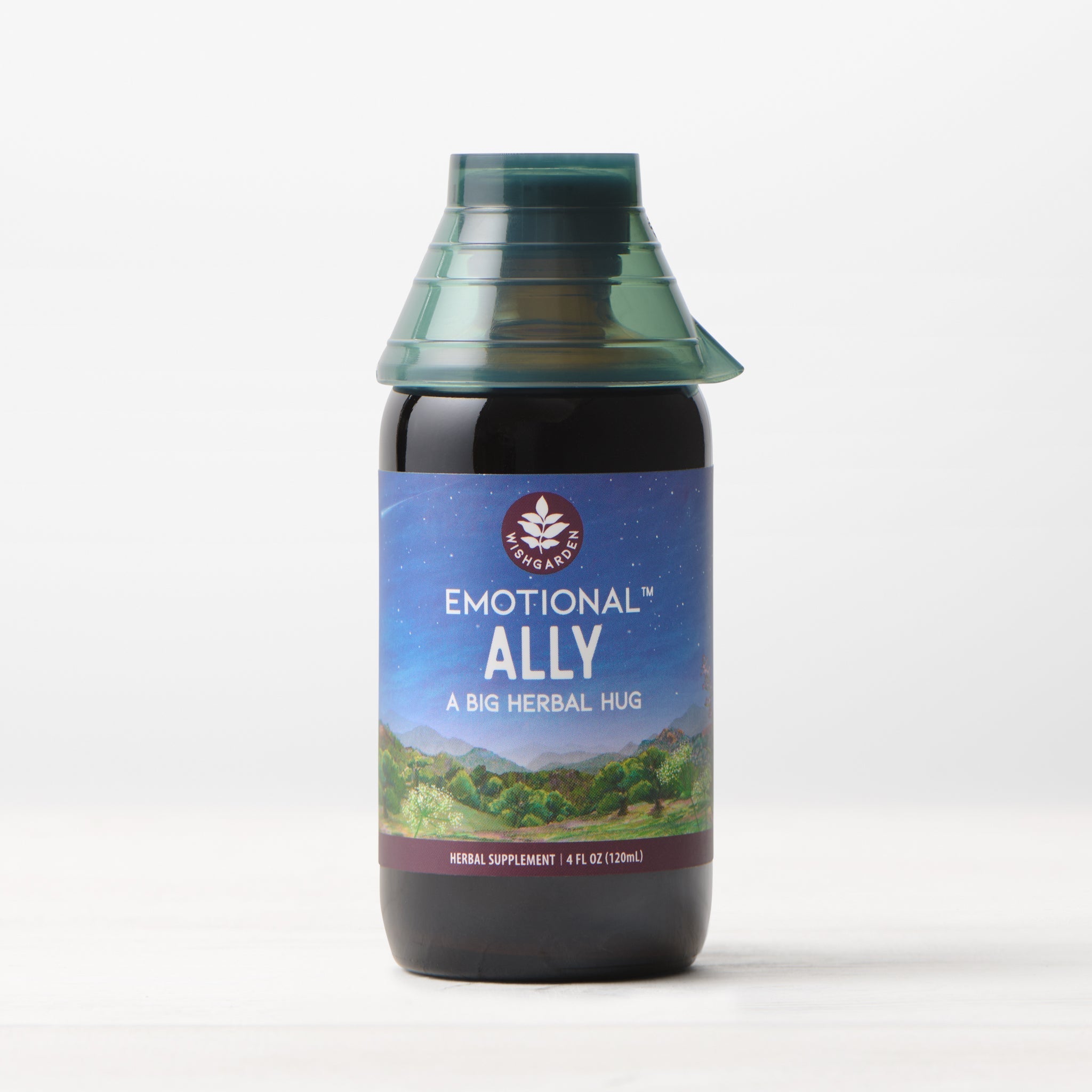 A dark bottle labeled Emotional Ally: A Big Herbal Hug sits on a white surface with a scenic landscape design and green cap—ideal for anyone looking for mood support with emotional support herbs.
