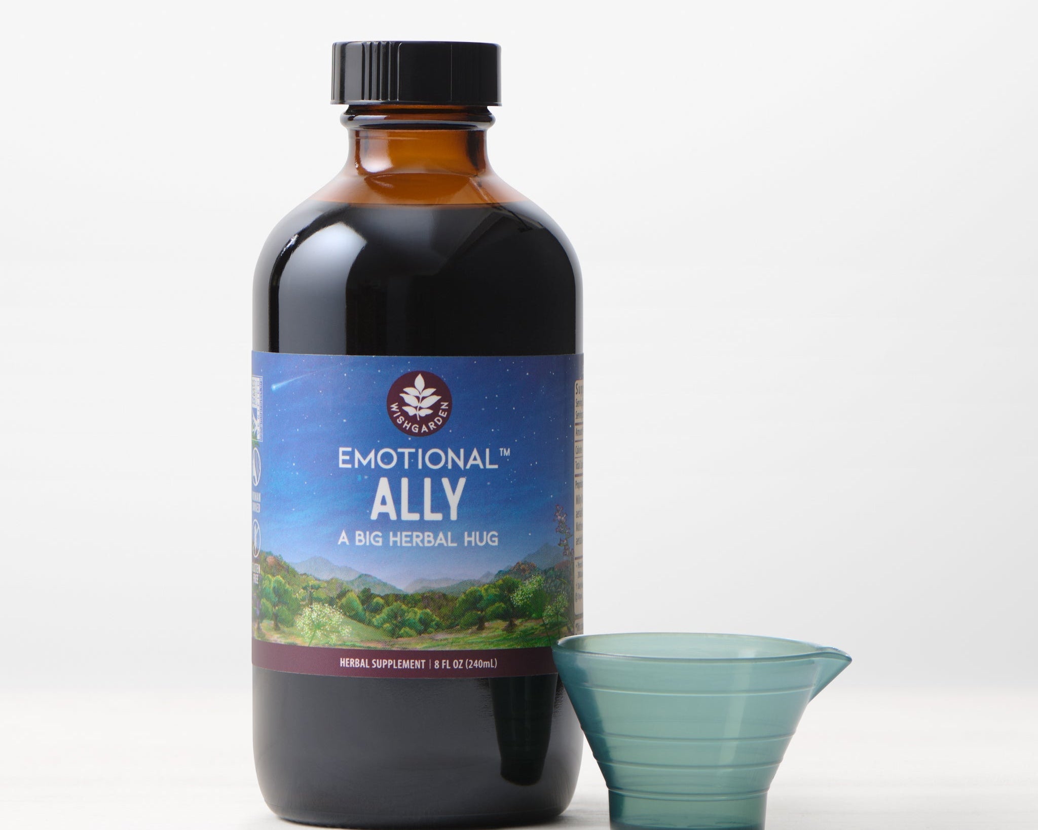 A brown bottle labeled "Emotional Ally: A Big Herbal Hug" with a small measuring cup sits on a light surface against a white background—ideal for those seeking mood support.