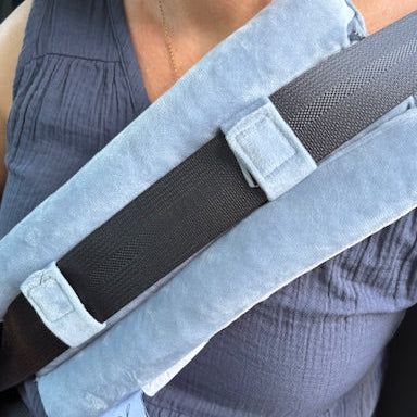 A person uses the Seat Belt Pillow, a blue cushion over a standard car seatbelt, for added comfort and chest support, reducing shoulder and chest pressure.