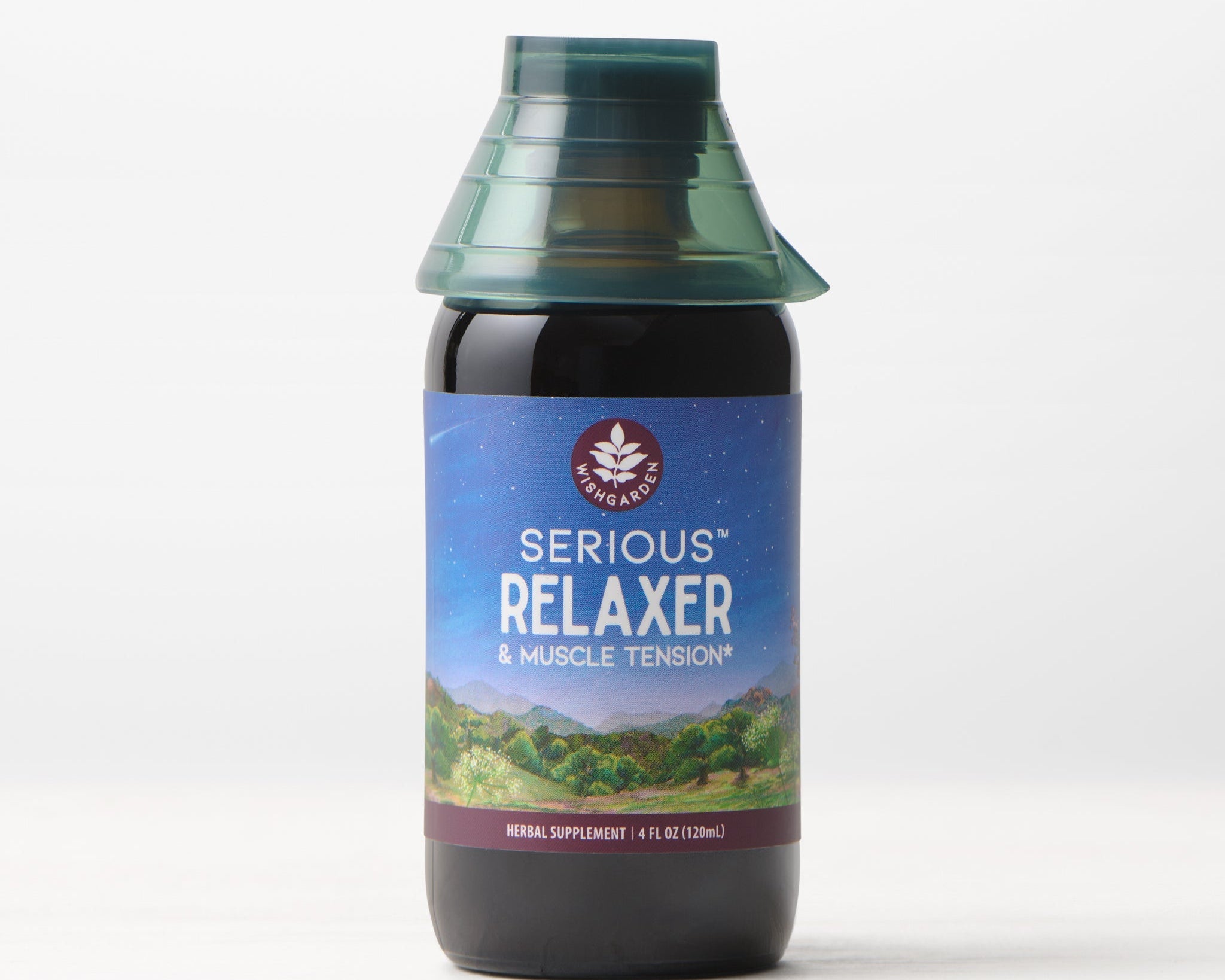A bottle of Serious Relaxer & Muscle Tension herbal supplement with a green cap sits against a light background; its label displays a peaceful mountain and starry night scene, emphasizing sleep aid and muscle tension relief benefits.
