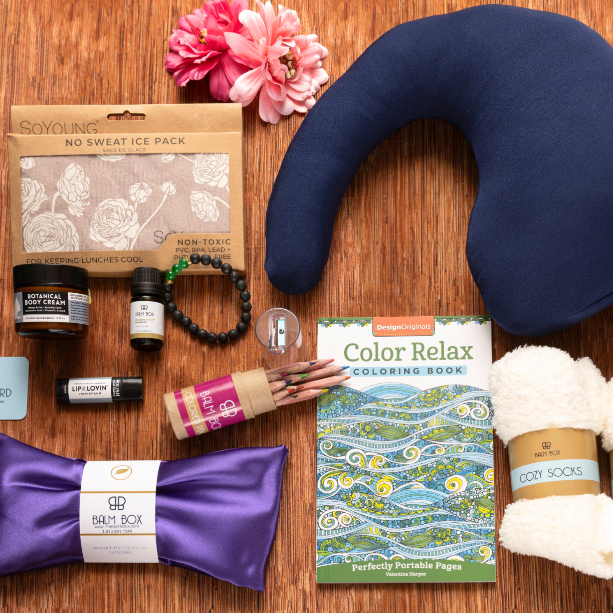 The Best Mastectomy Care Package includes a neck pillow, cozy socks, lotion, coloring book with pencils, ice pack, lavender pack, lip balm, card, and pink flowers—thoughtfully arranged for self-care after surgery.