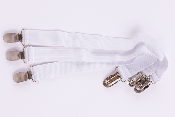 Three white elastic bed sheet straps with metal clips, side by side on a plain white background—perfect for securing your Sleep Again Pillow System or holding contoured side pillows in place.