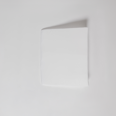 An Individual Wedge Pillow Sold Separately rests on a plain white surface, casting a soft shadow to the upper right—mirroring the crisp, clean feel of customizable bedding in a serene bedroom.