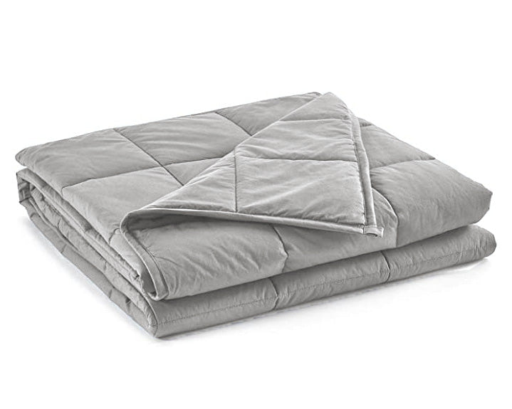 The Pillowtex Weighted Blanket, in light gray with a soft texture, is shown neatly folded on a white background. A corner is turned over to reveal its thickness, detailed stitching, and premium glass bead filling.