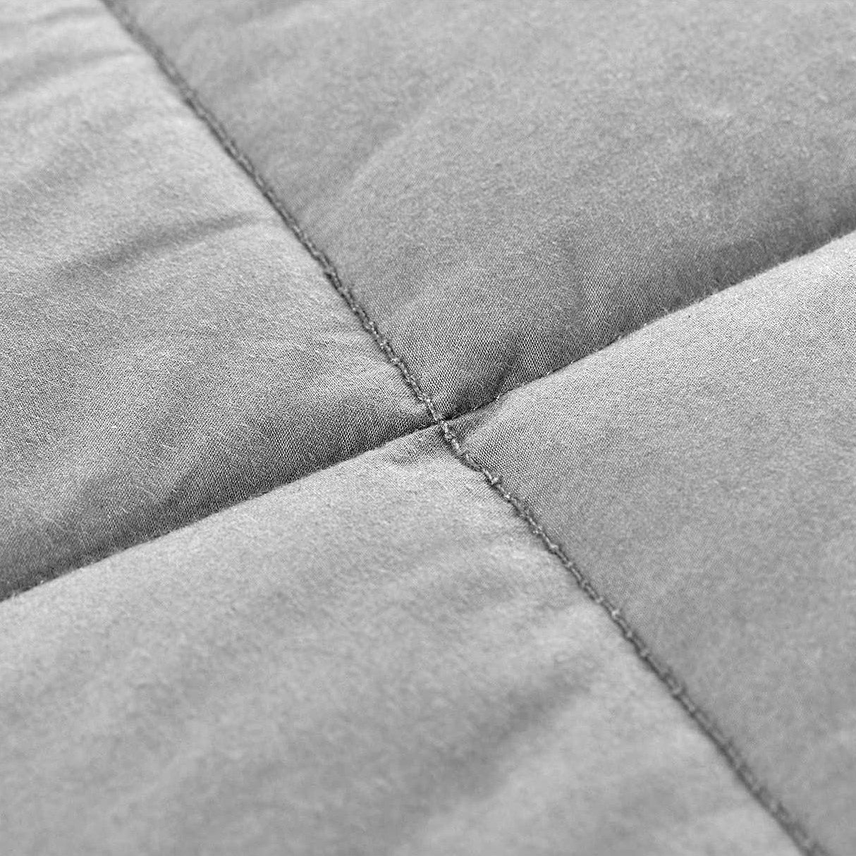 Close-up of the gray, quilted fabric with visible grid stitching highlights the texture and softness of the Pillowtex Weighted Blanket for adults.