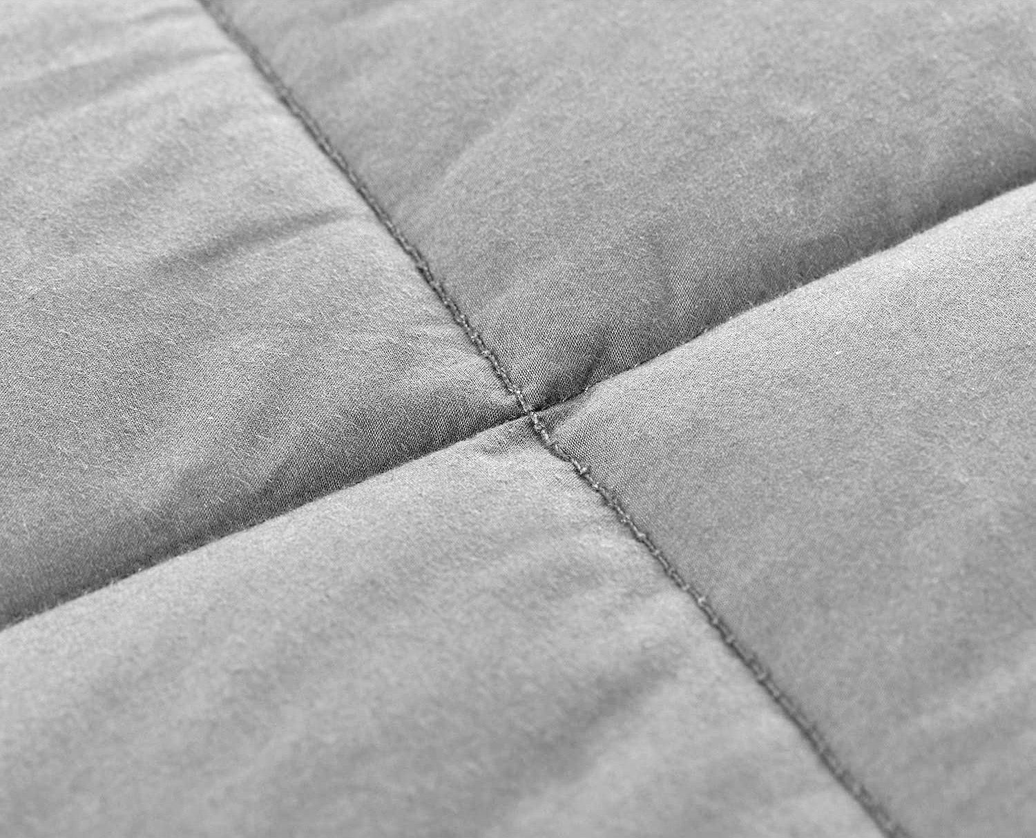 Close-up of the gray, quilted fabric with visible grid stitching highlights the texture and softness of the Pillowtex Weighted Blanket for adults.