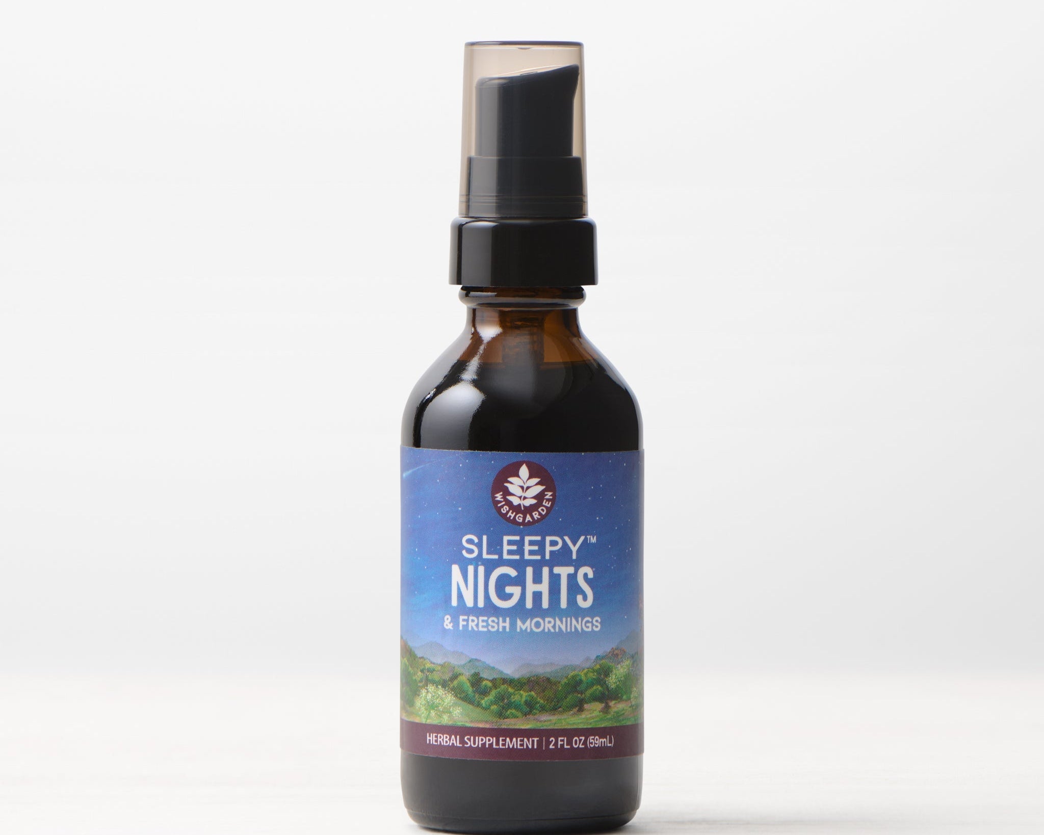 A brown glass bottle of Sleepy Nights & Fresh Mornings sleep supplement with a spray top rests on a white surface. Its label, featuring a night sky and green hills, faces forward against a light background.