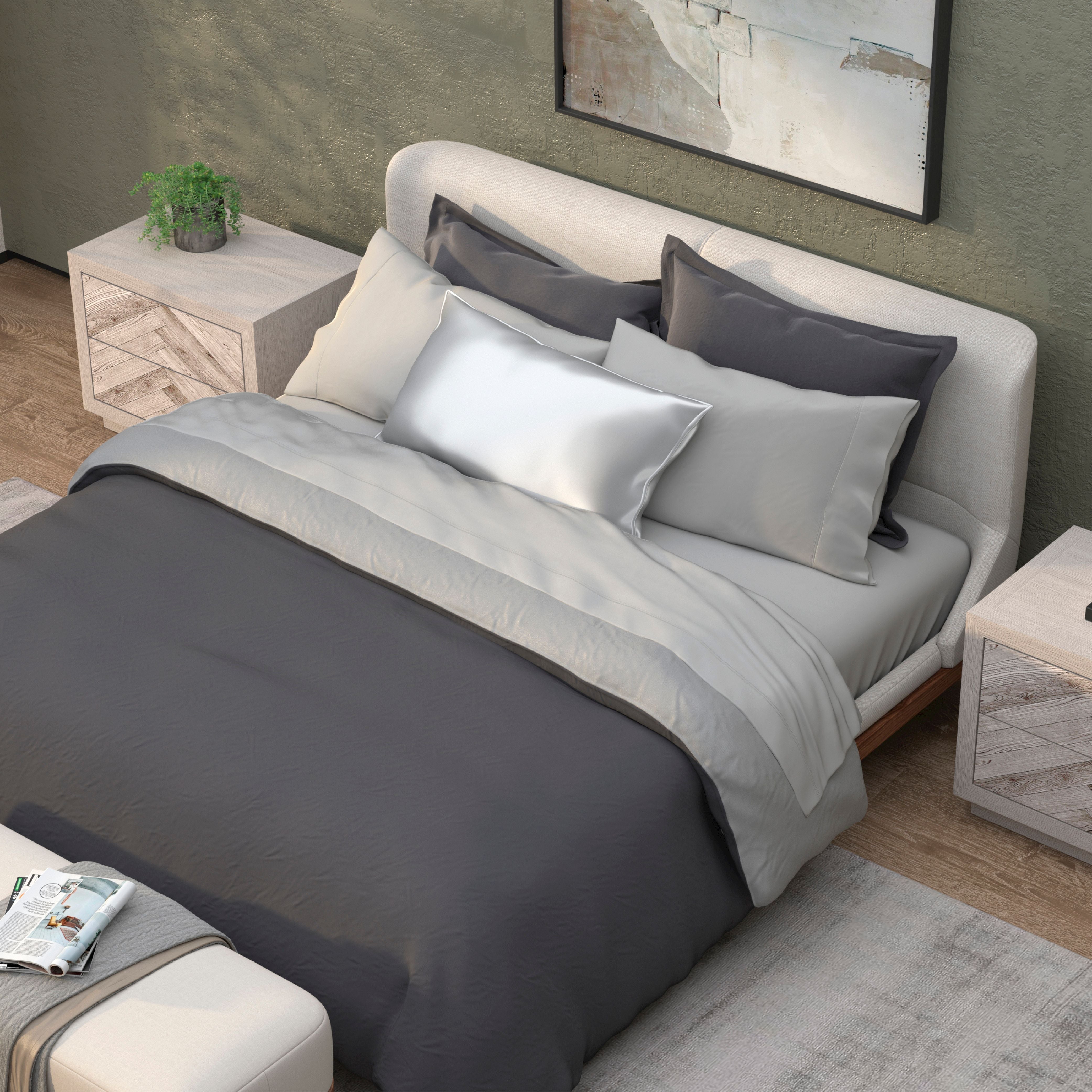 A neatly made bed with PureCare Duvet Cover | Cooling Bamboo in dark and light gray, multiple pillows, and wooden nightstands on each side topped with a small plant and a book, set in a modern bedroom.