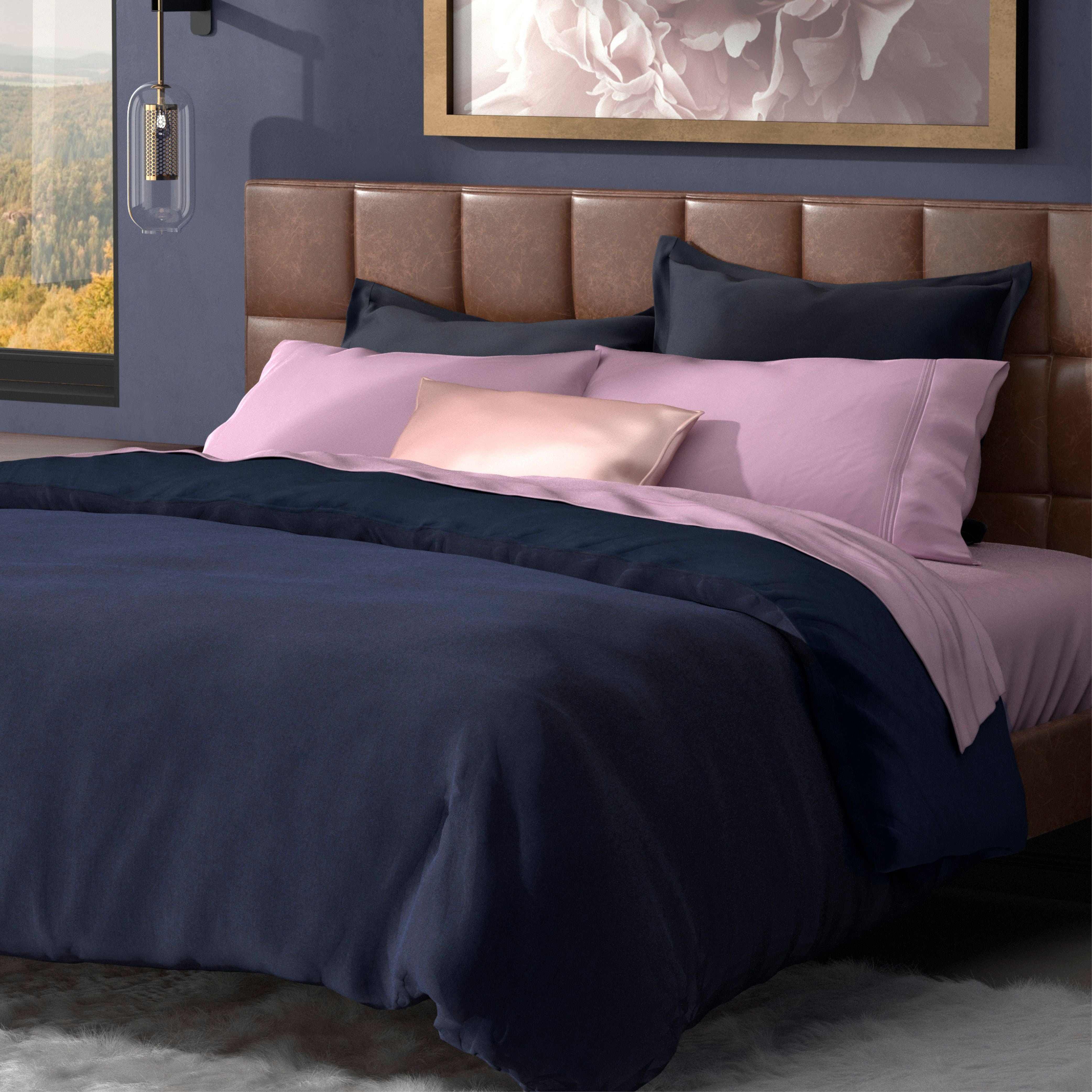 A modern bed with a brown upholstered headboard features navy blue and light pink bedding, a satin pink accent pillow, and the PureCare Duvet Cover | Soft Touch Bamboo. A soft rug lies below, with abstract wall art above the bed.